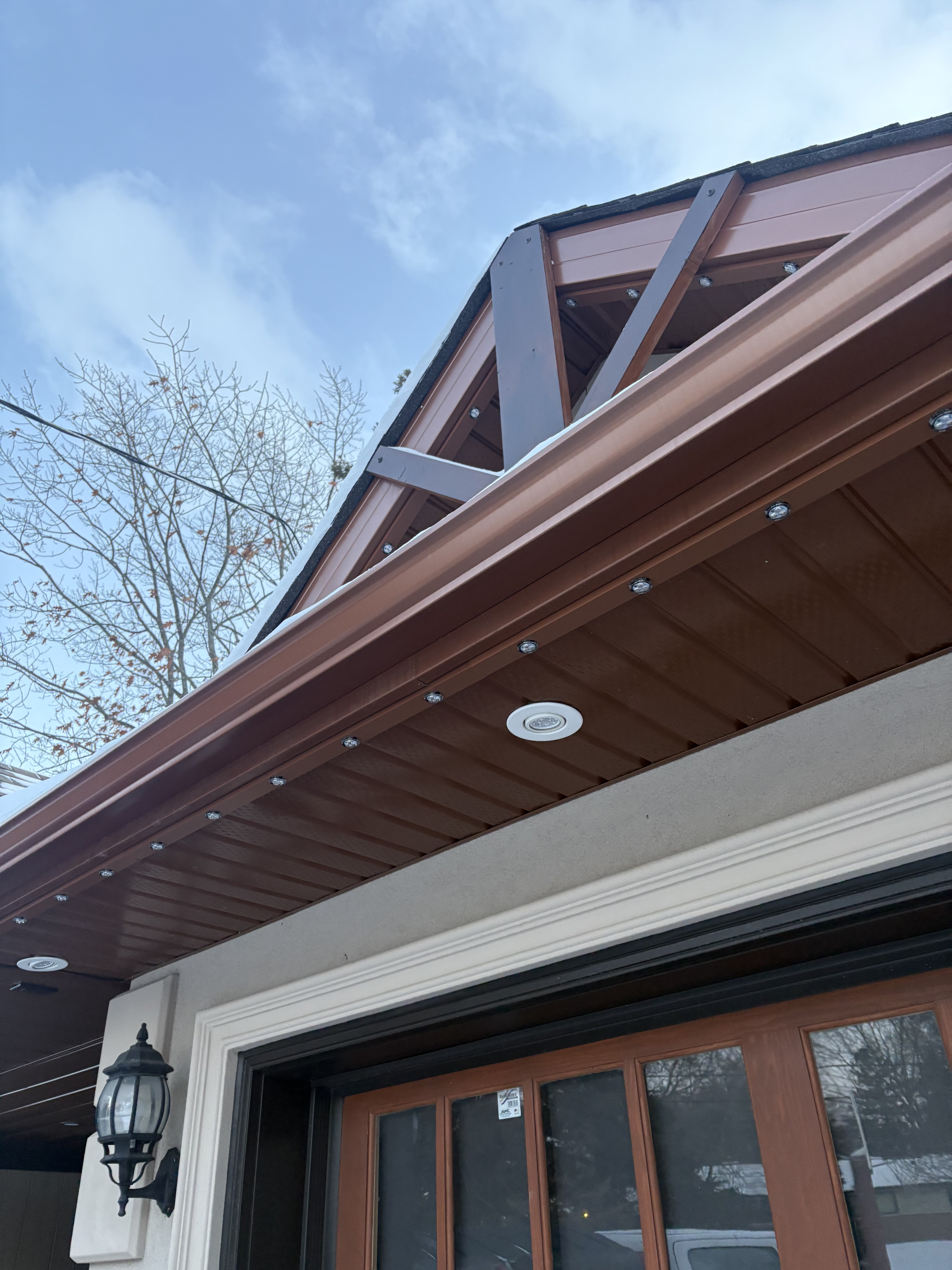 Permanent lighting track installed along a brown soffit and roofline