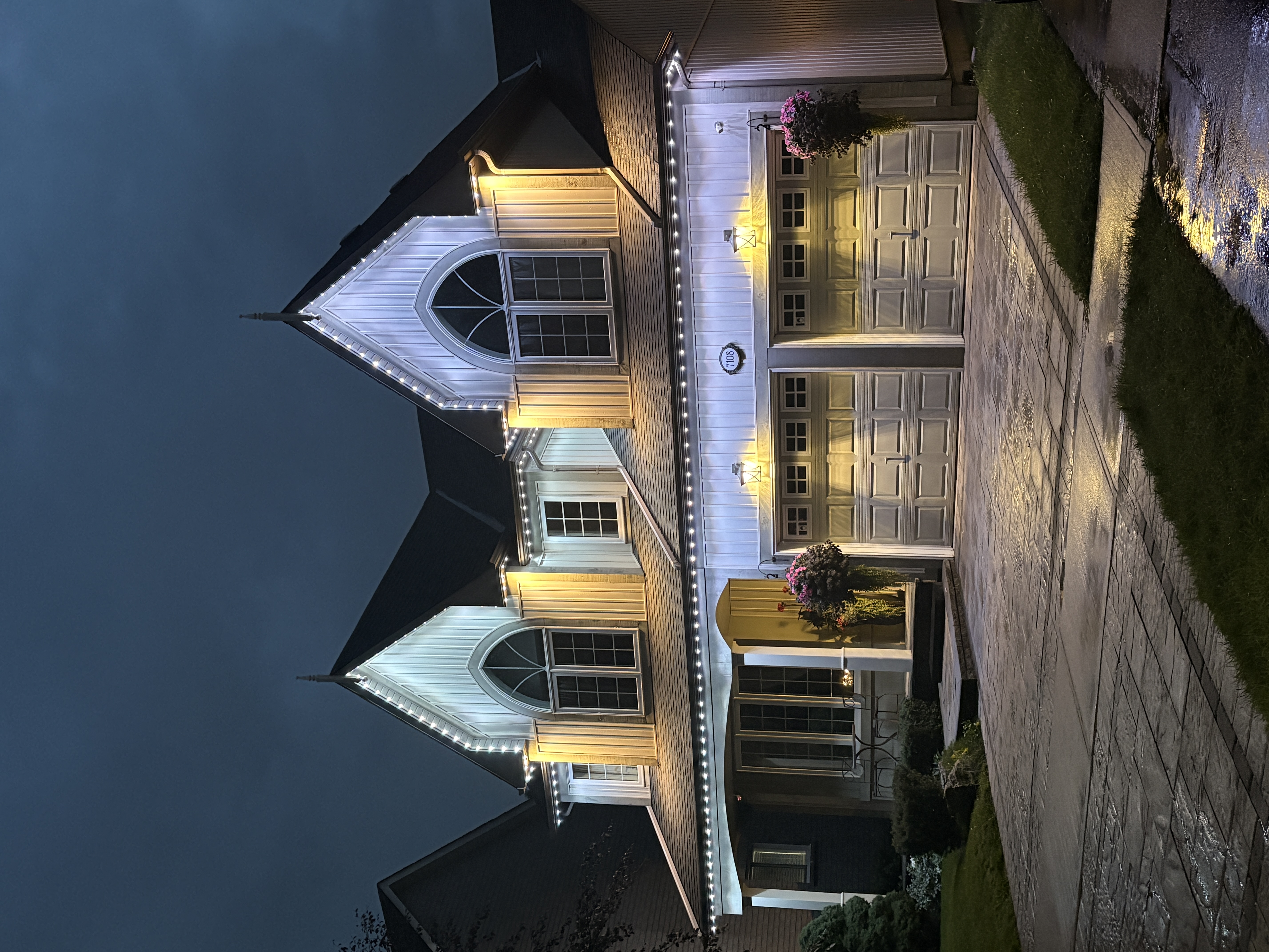 Pure white permanent lighting along the rooflines of a two-storey home