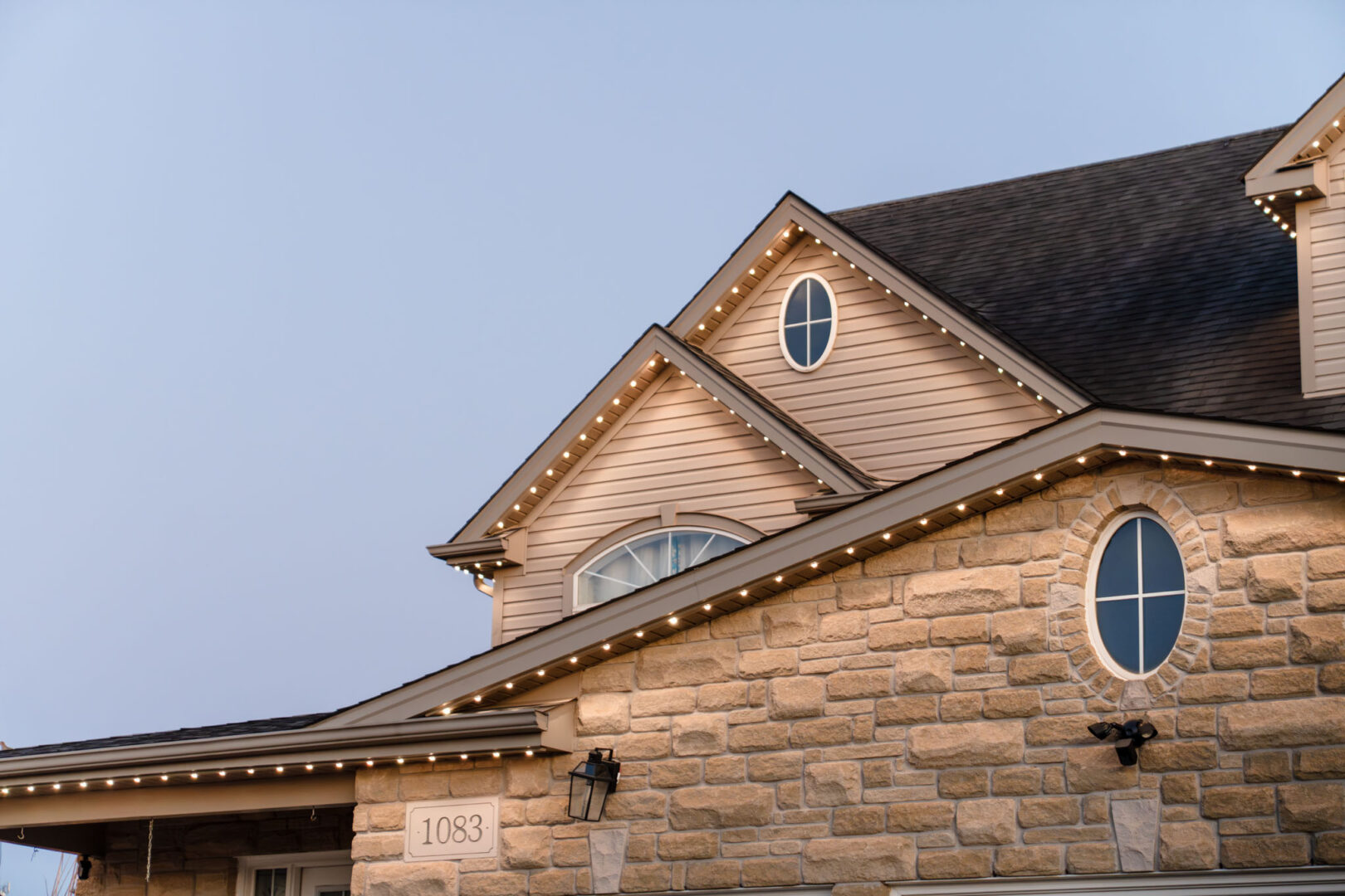 Close-up of permanent track lighting on a stone home at dusk