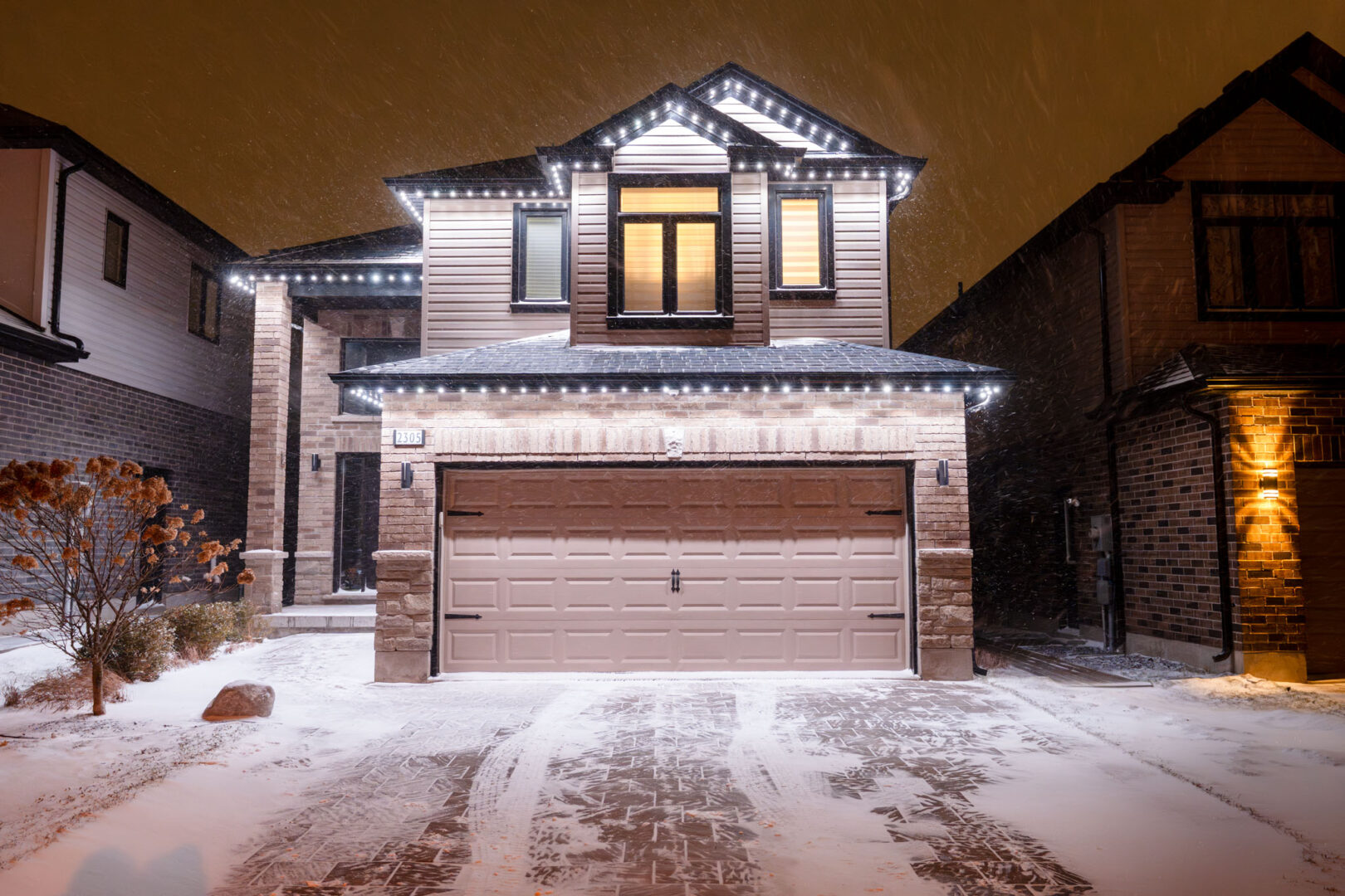 White permanent lighting on a two-storey home in snow