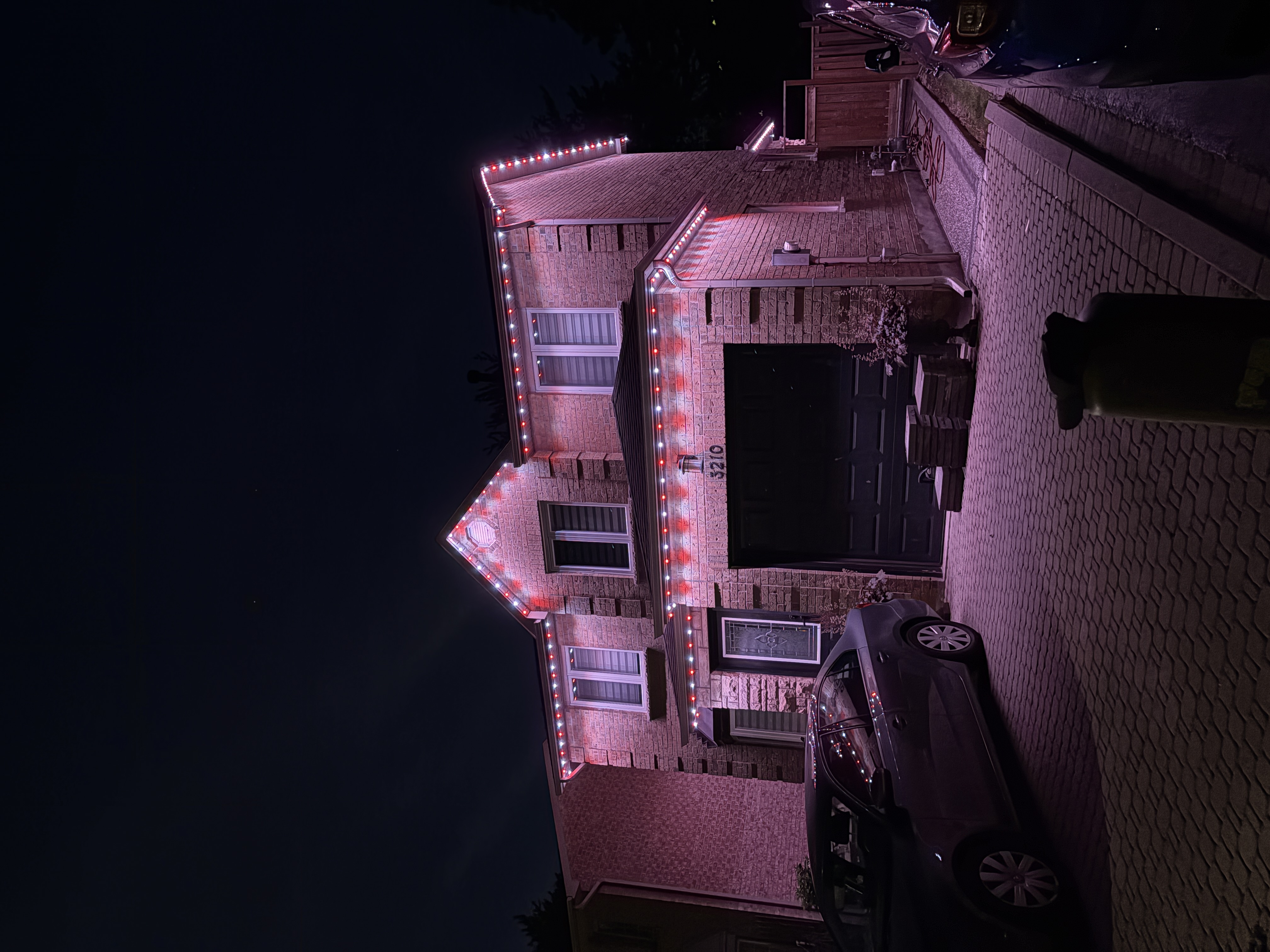 Pink and white permanent lighting on a brick home