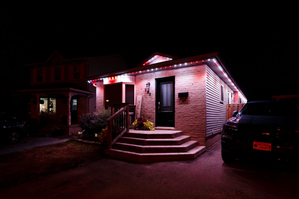 Red and white permanent lighting on a small brick home
