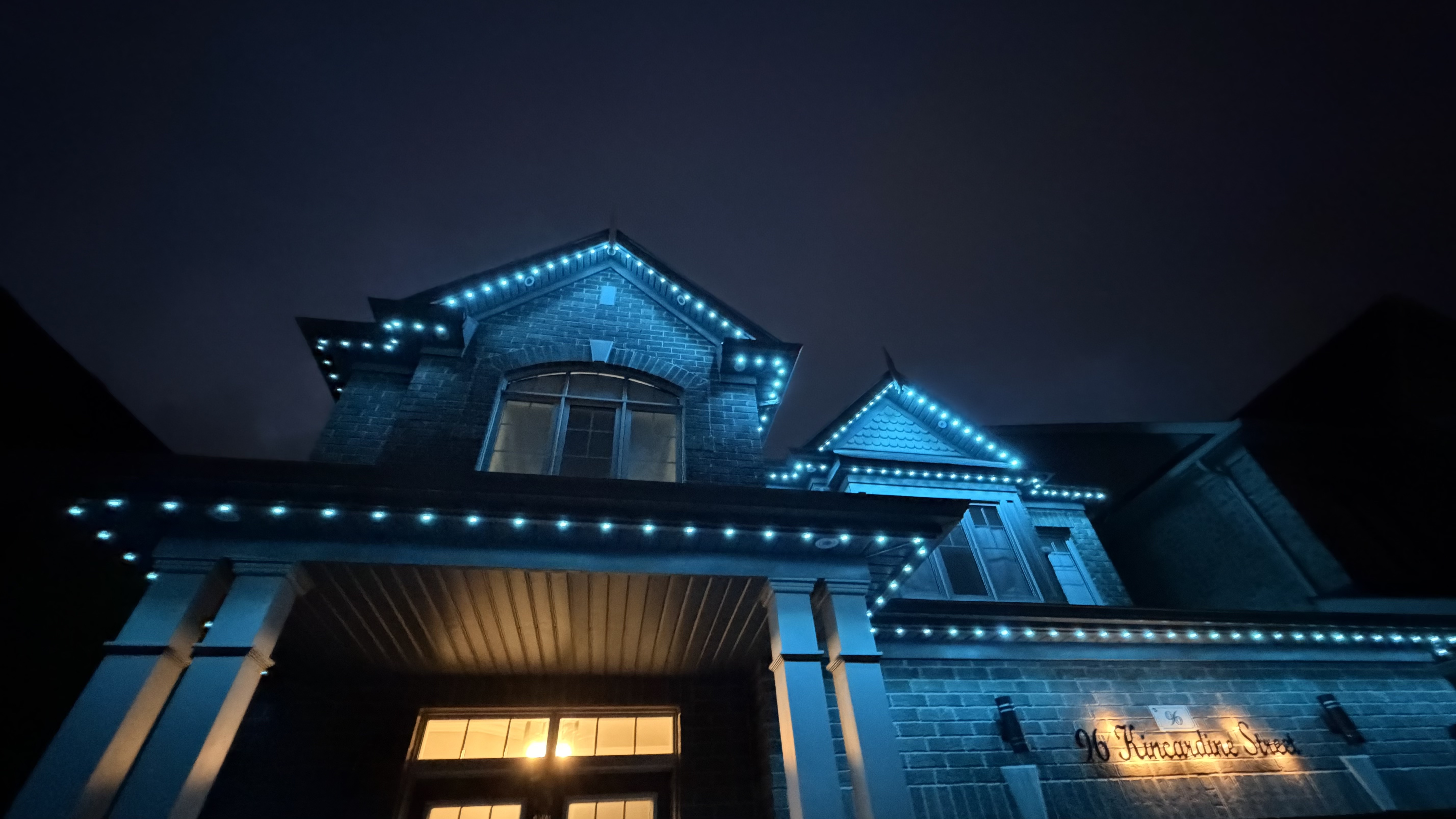 Teal permanent lighting on a brick home entrance