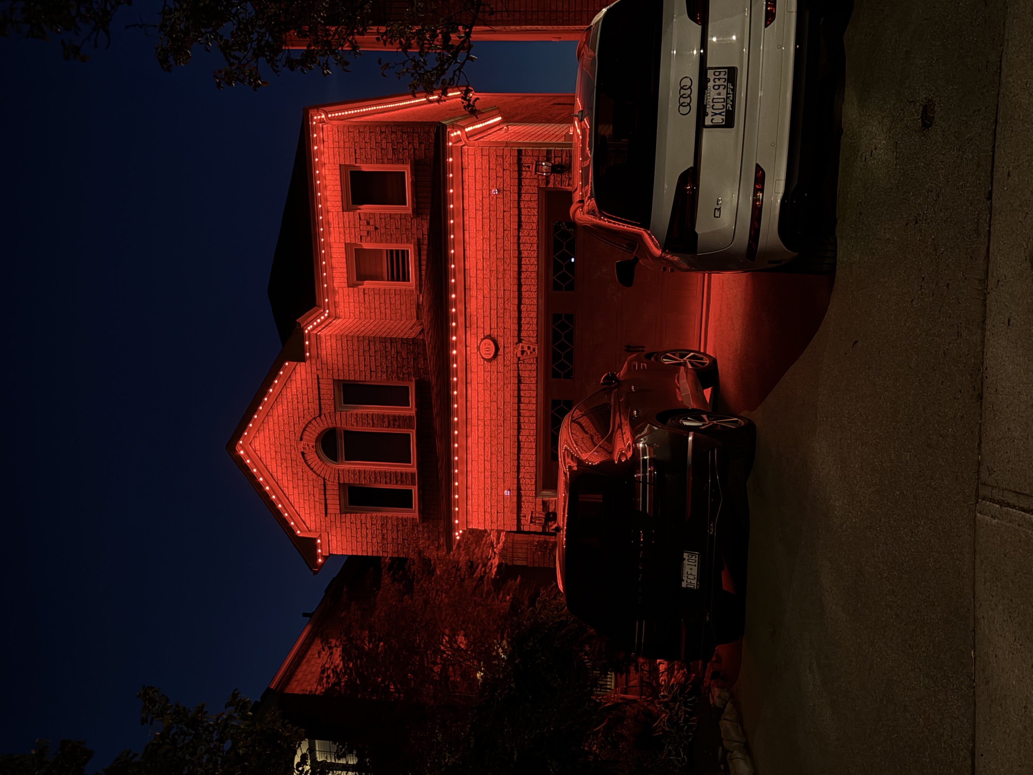 Red permanent lighting on a brick two-storey home