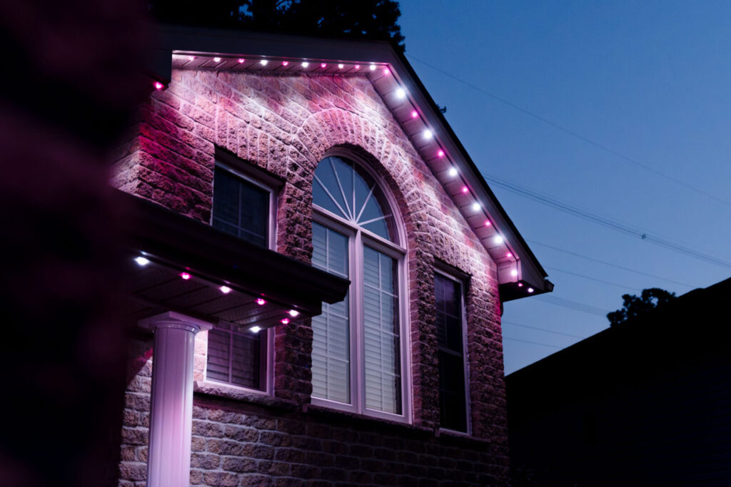 Warm white permanent lighting on a brick home with a flag