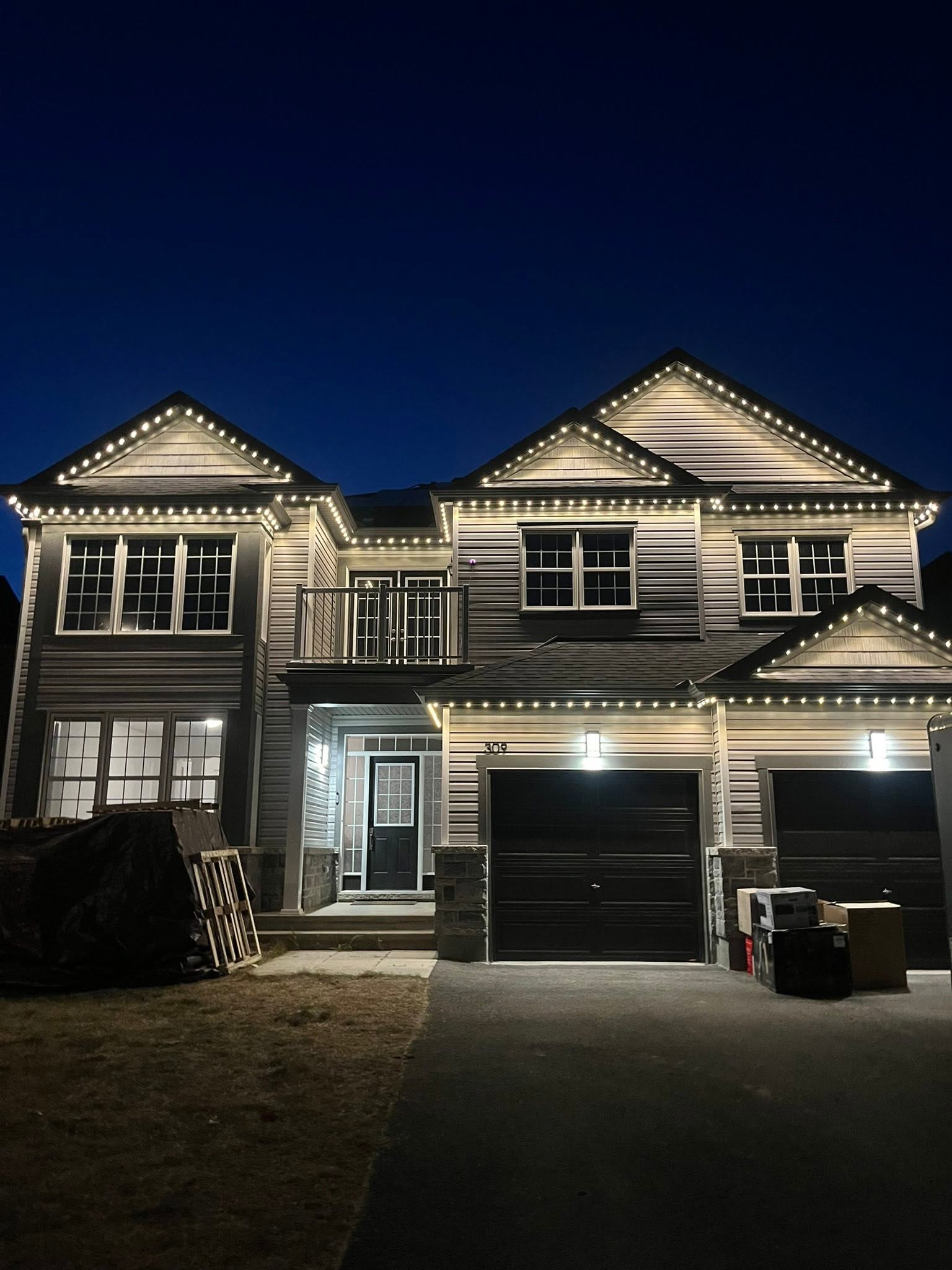 Pure white permanent lighting outlining the rooflines of a two-storey home at night