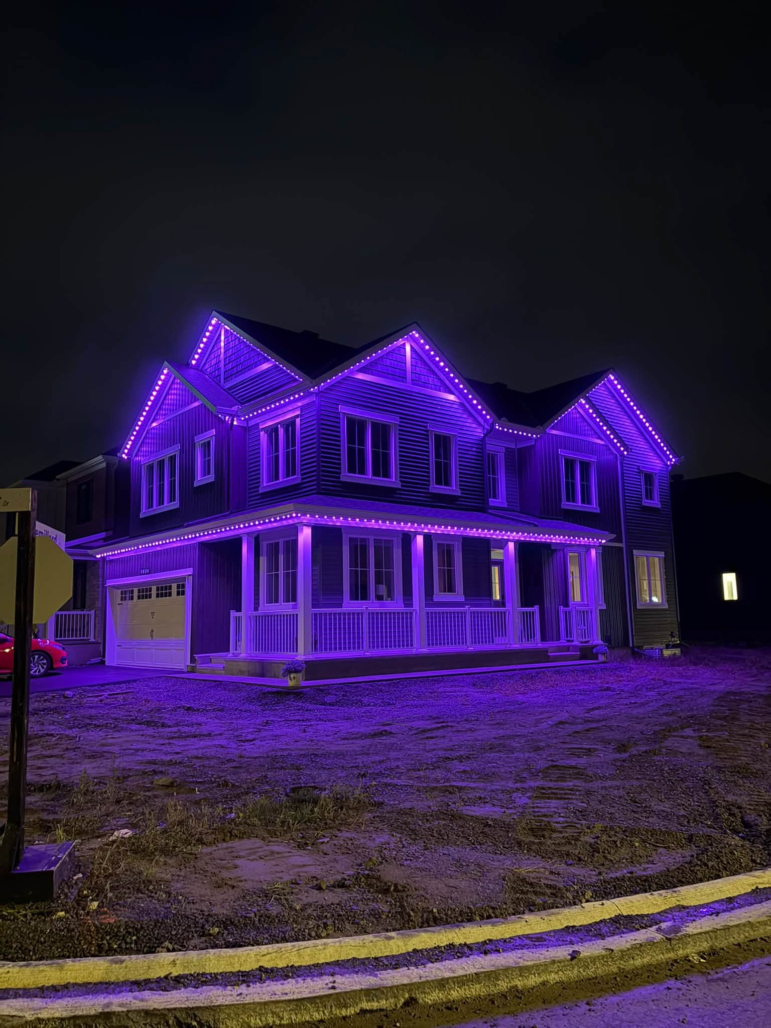 Purple permanent lighting outlining a large two-storey home at night