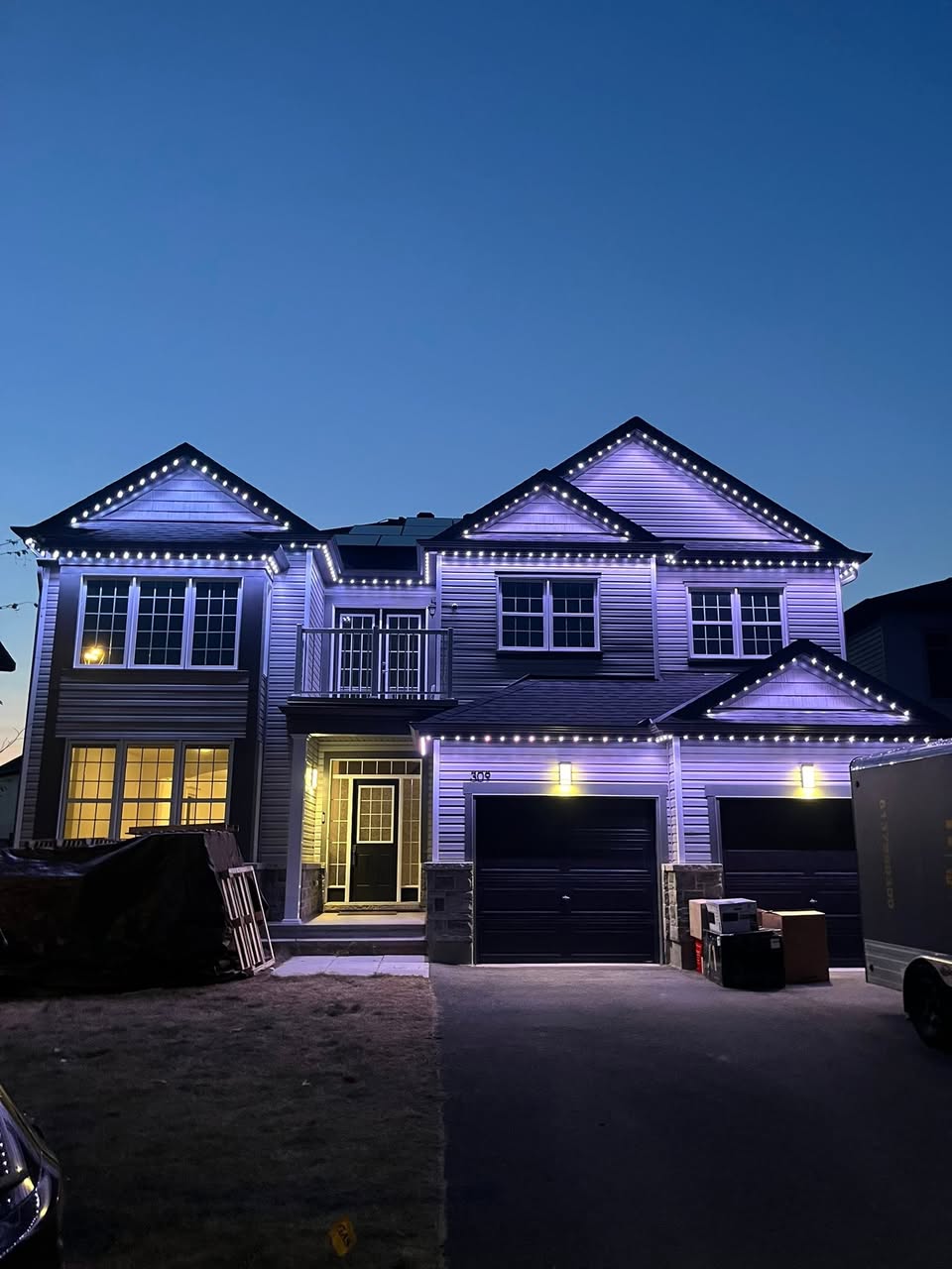 Cool white permanent lighting outlining a modern two-storey home at dusk