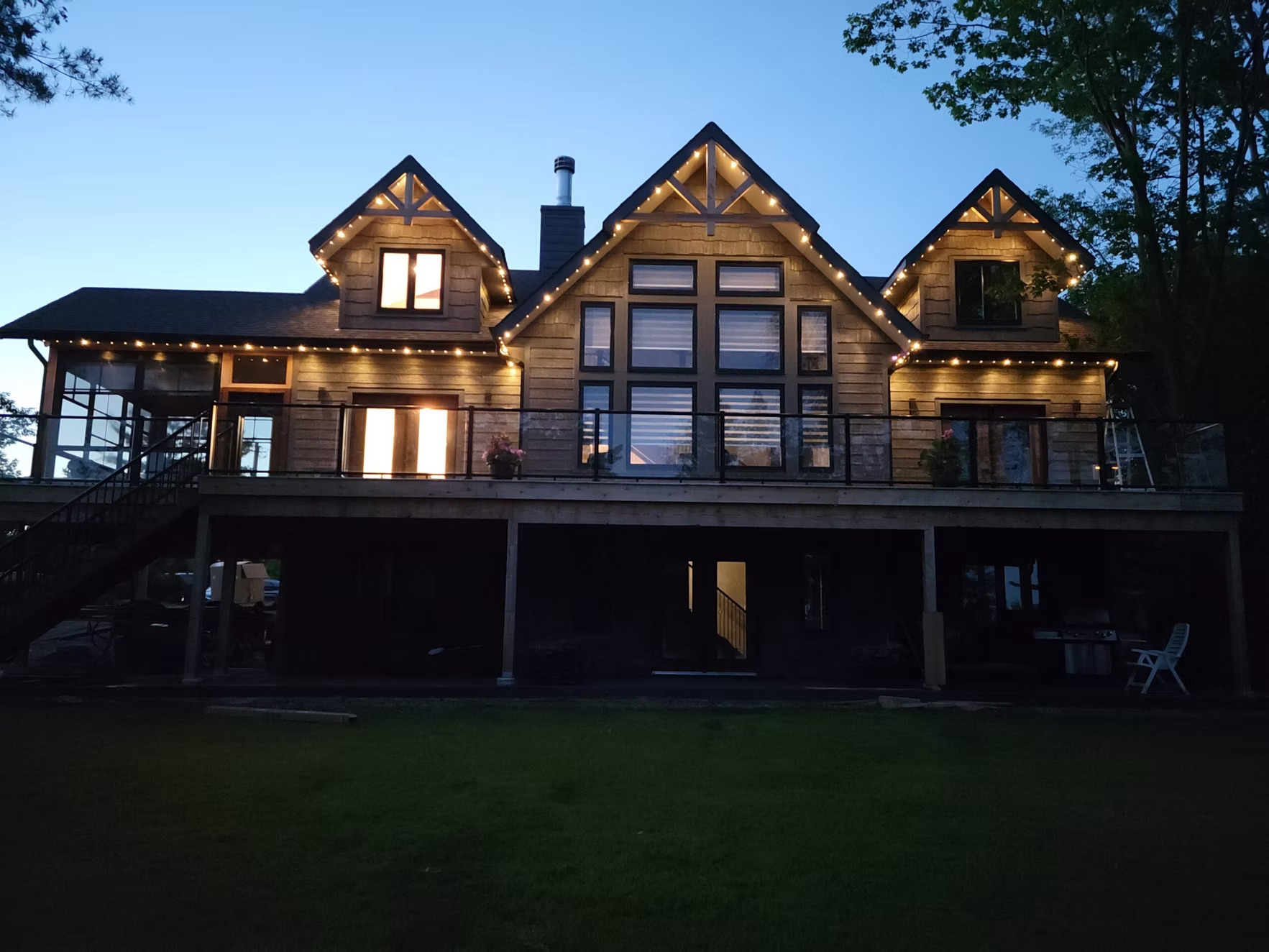 Warm white permanent lighting across the rooflines of a large custom home