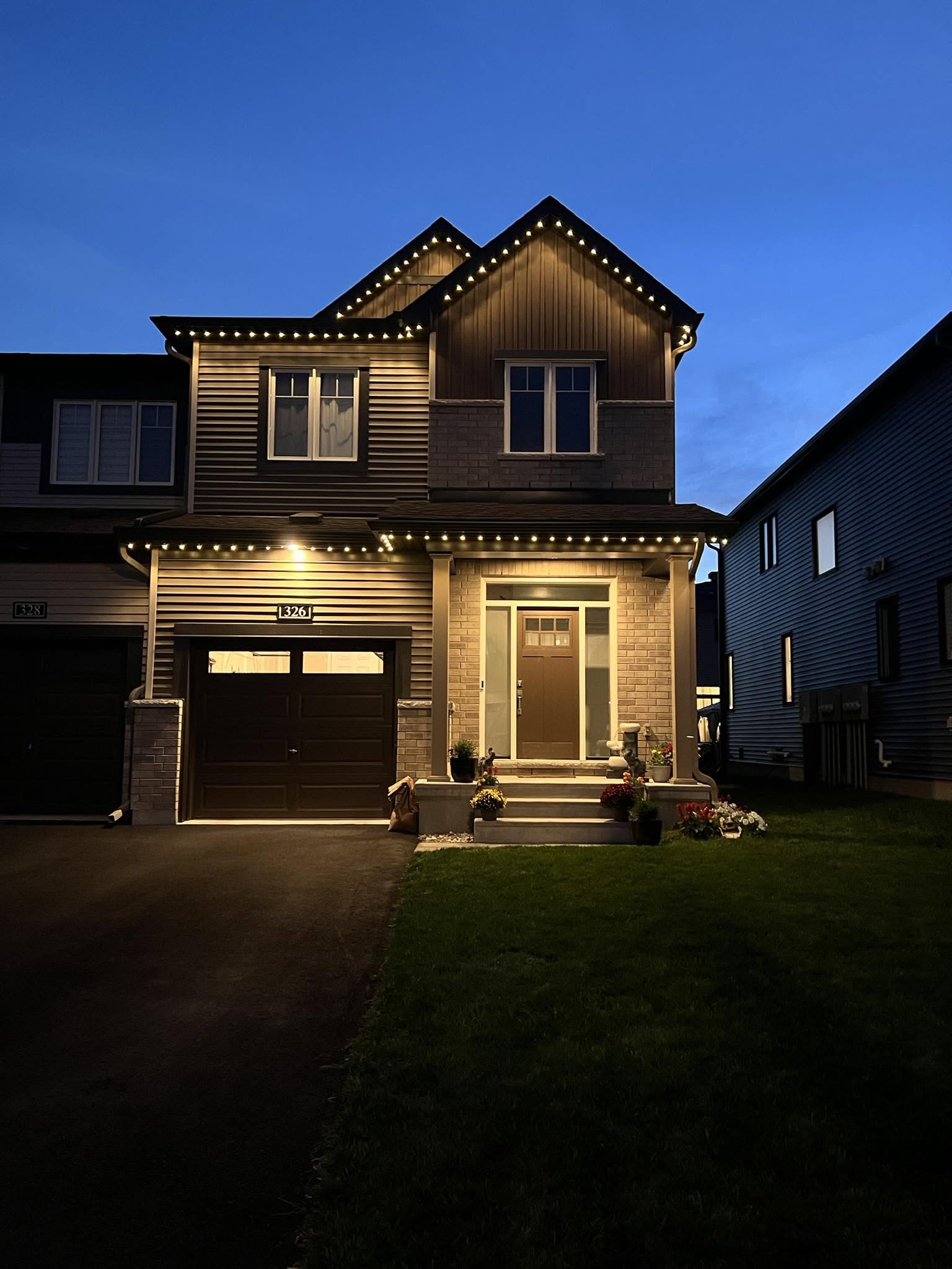 Warm white permanent lighting along the roofline of a two-storey home at dusk