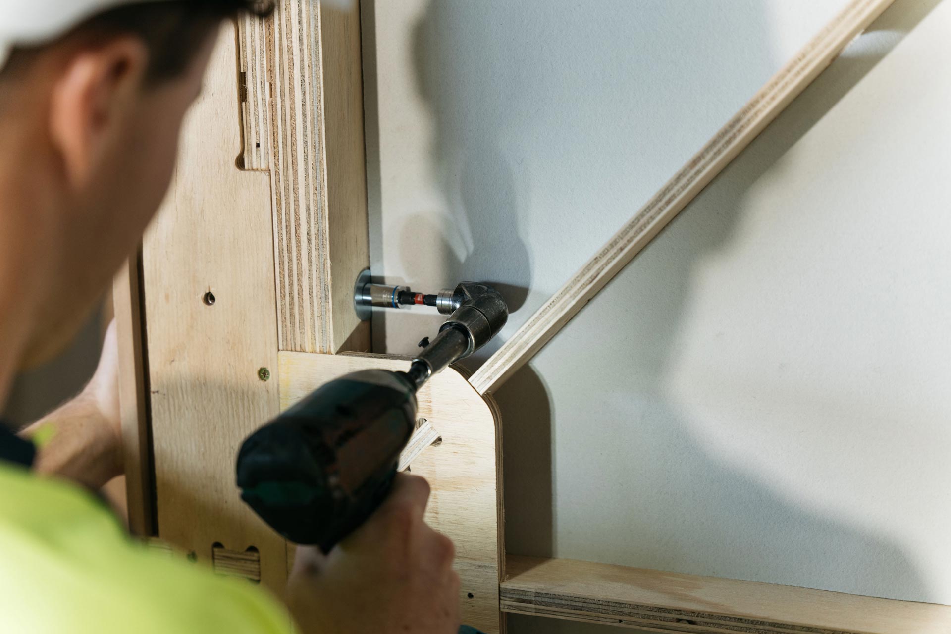 Close up of a builder using a tool to screw two XFrame panels together.
