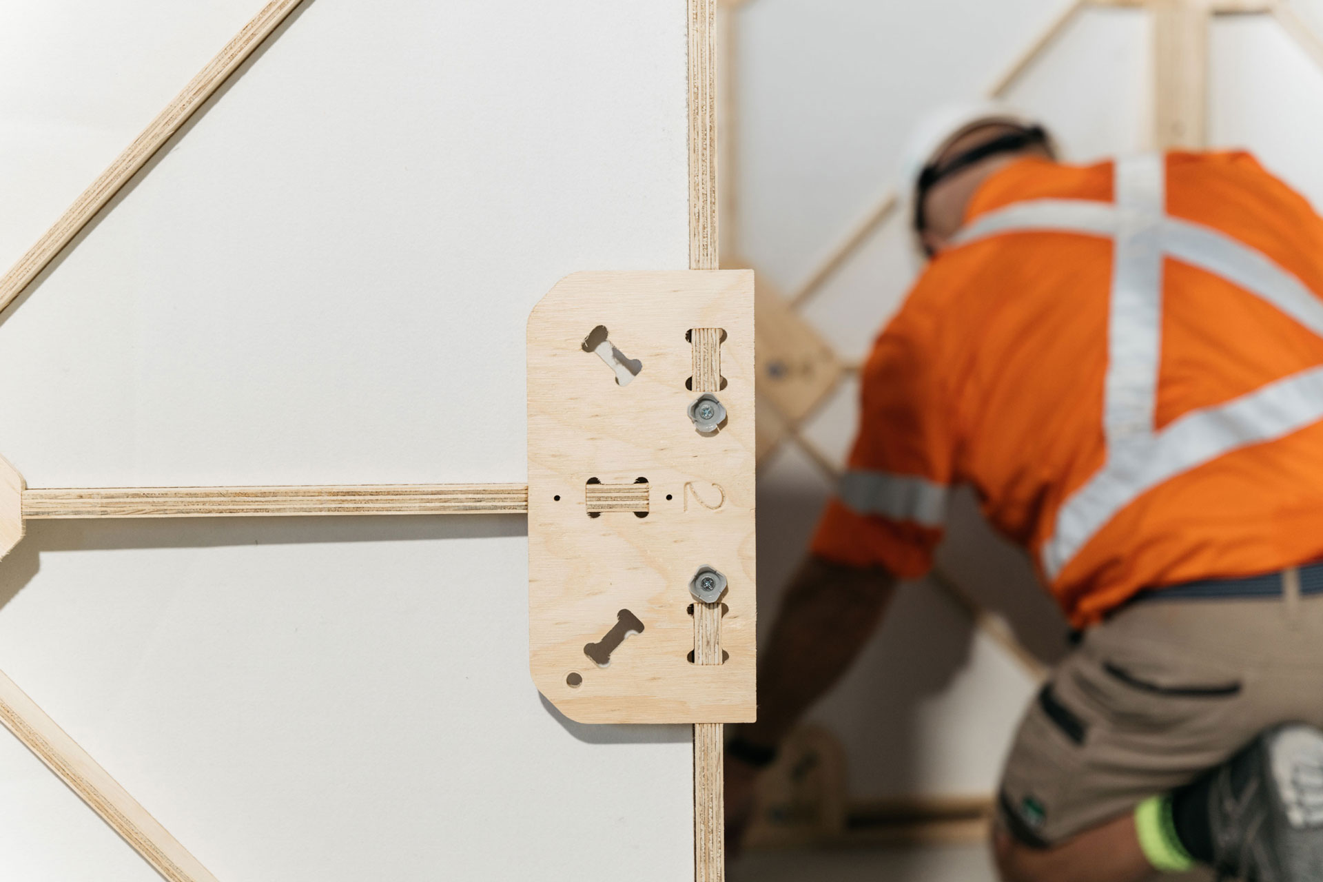 A close up of Part 2 on an XFrame panel with insulation in the panel. A builder in an orange high vis is in the background. 
