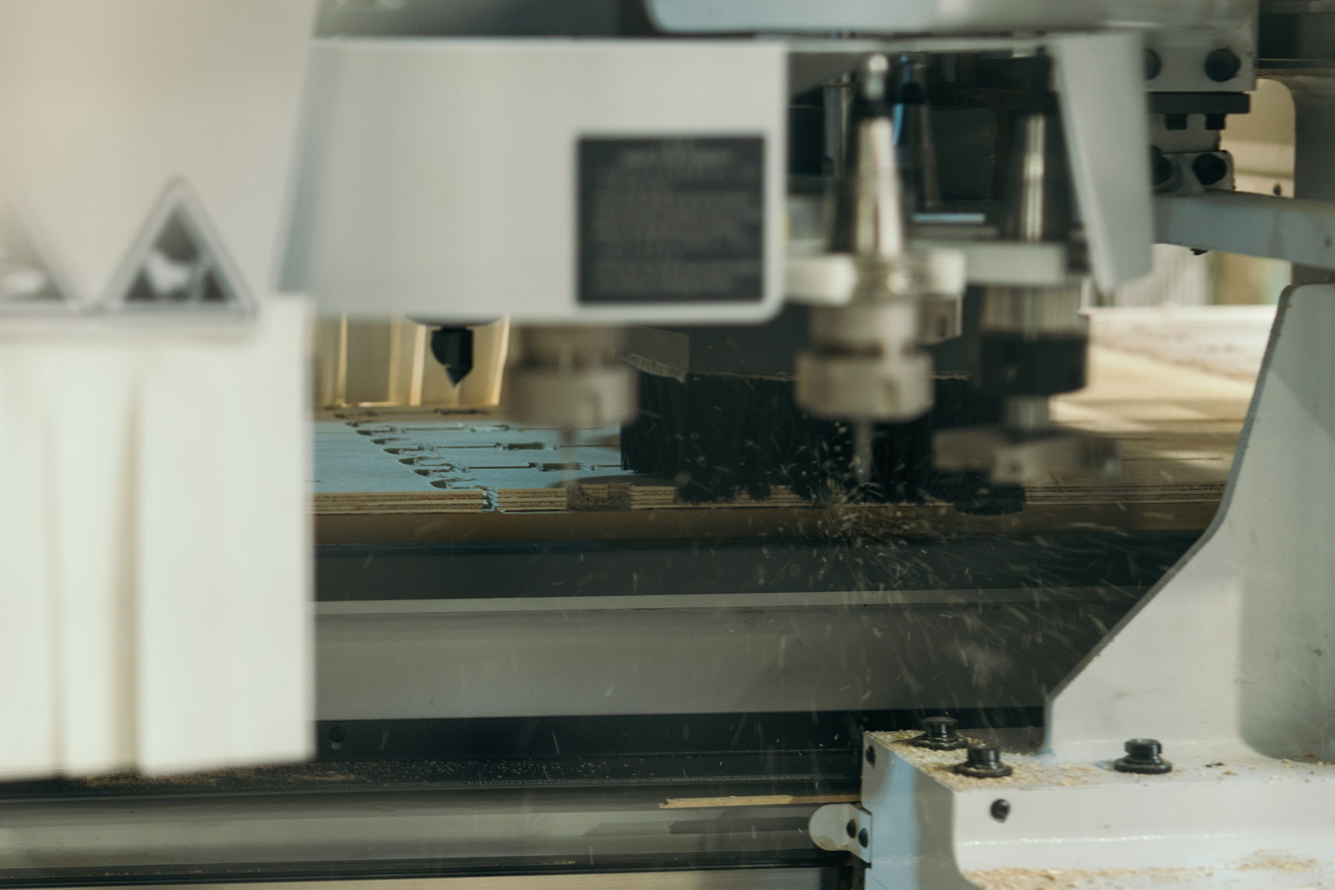 A close up of the CNC tool cutting XFrame parts on a sheet of plywood. 