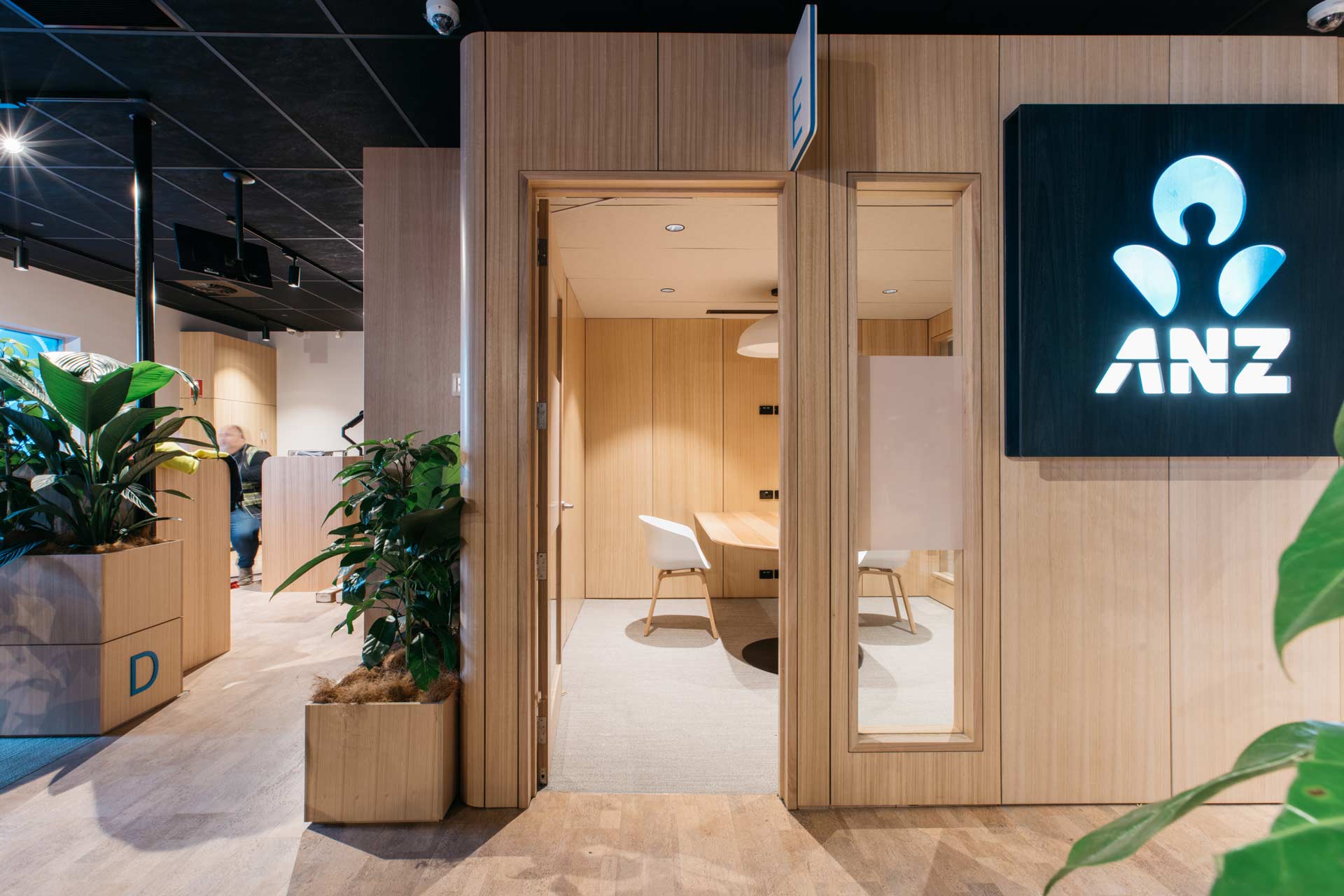 Front on view of an ANZ meeting room made out of XFrame, with tasmanian oak linings and planters around the meeting room.