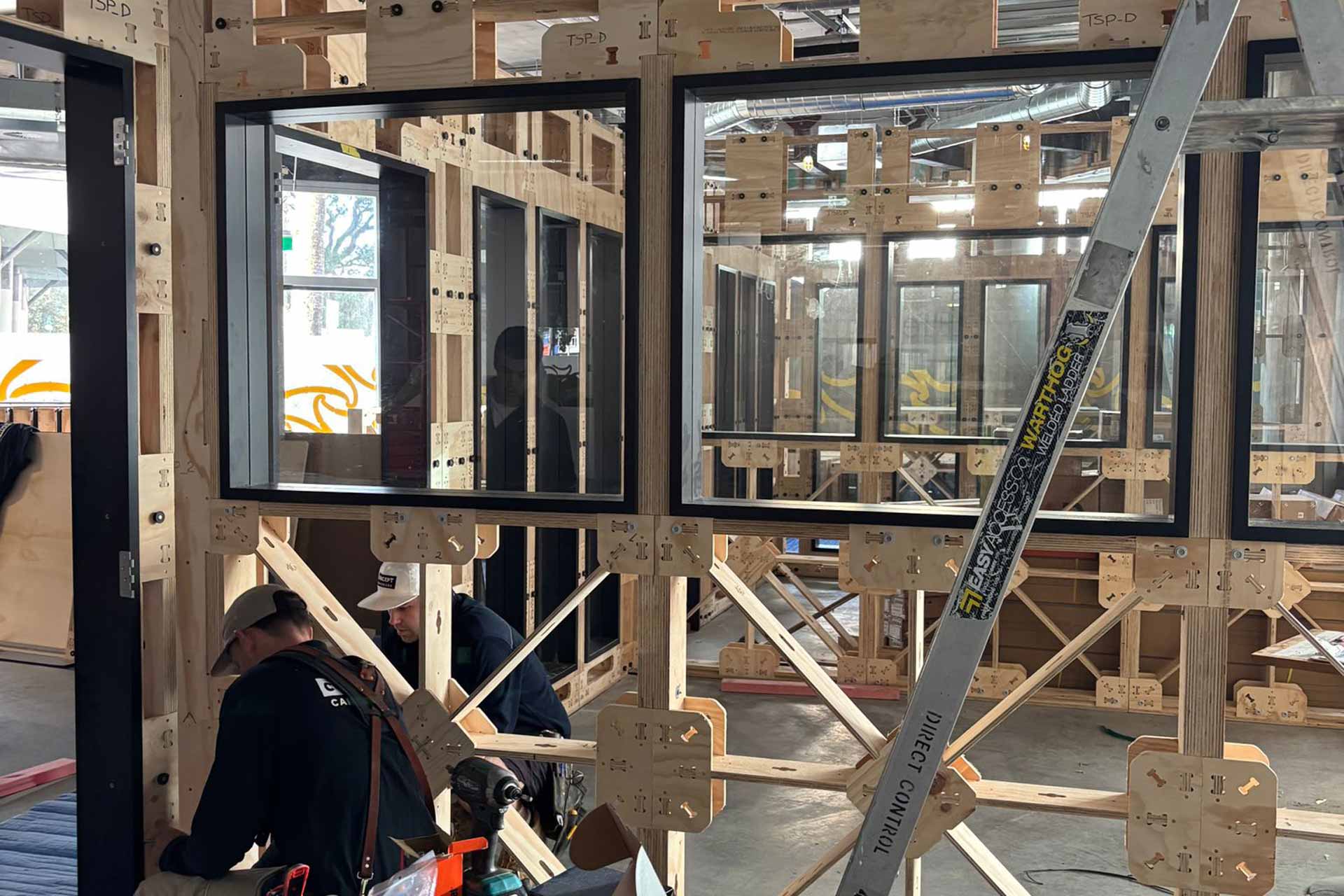 Construction of WOTSO Te Toangaroa, bare XFrame panels with windows up, with two builders working on the bottom left.