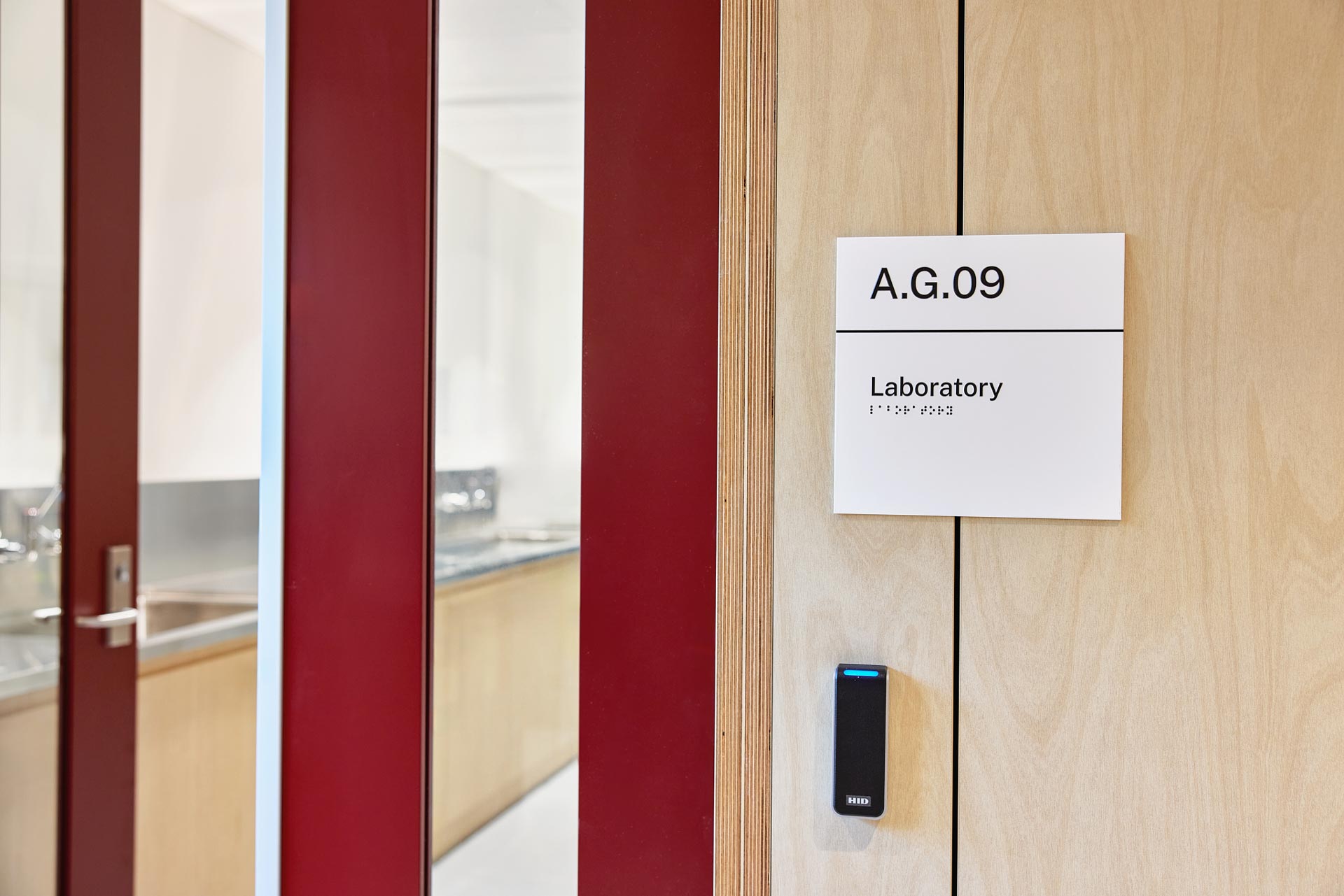 Close up of a Laboratory, looking in from the red door and window, with a sign saying laboratory and a key card scanner.