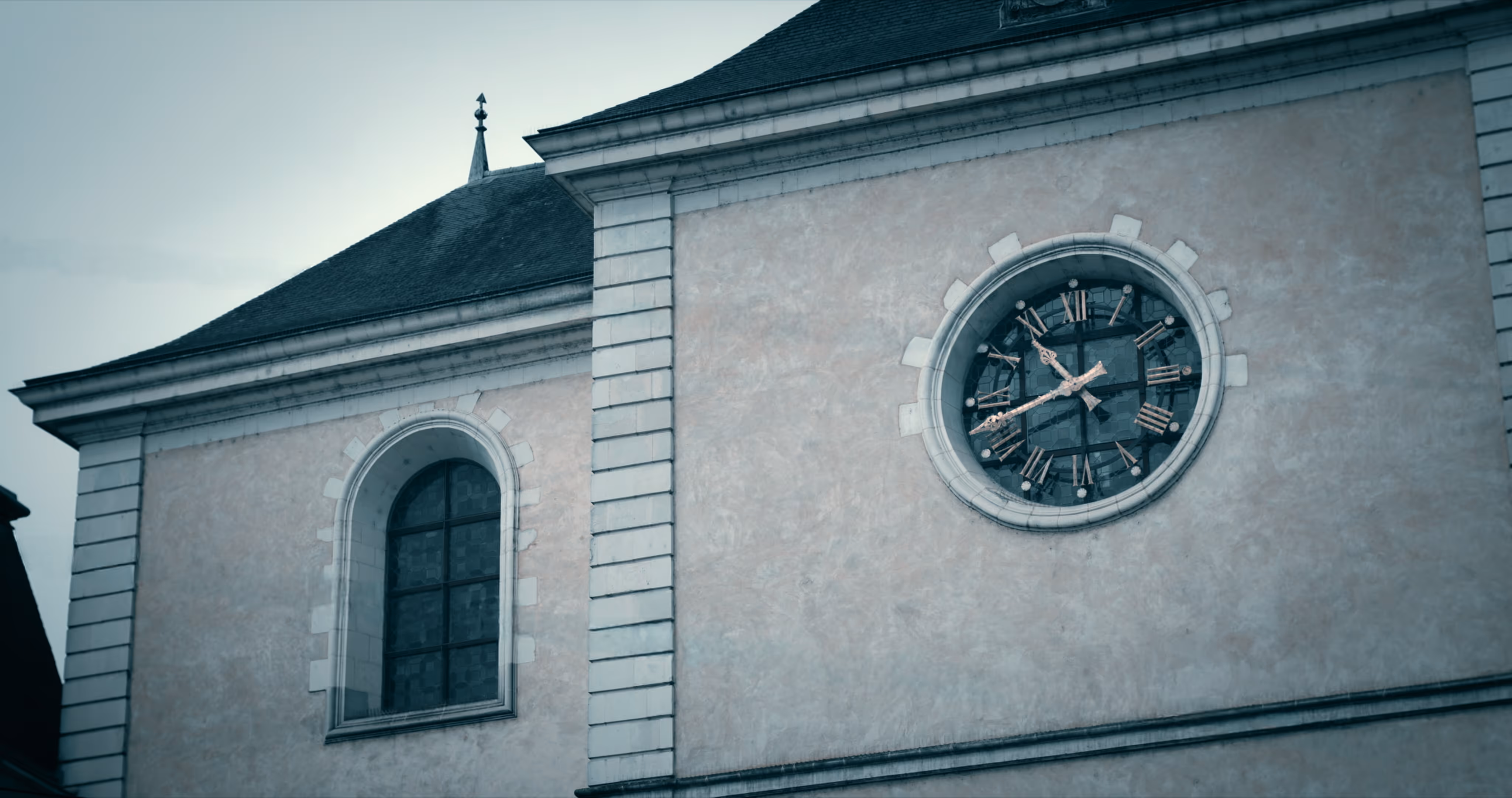 Clock tower on a building showing 6:45 with a rounded window to its left.