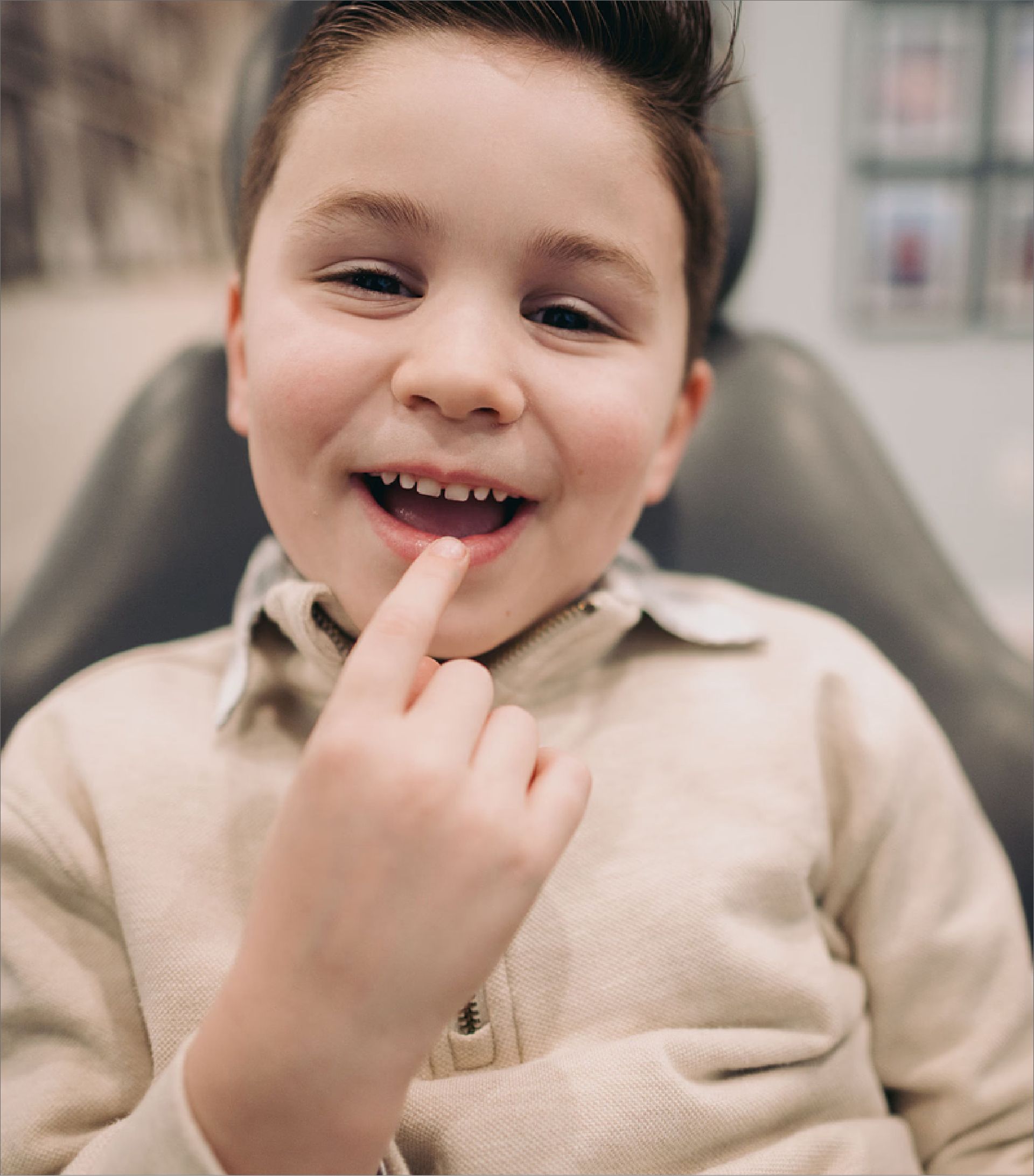 Smiling boy showing his lost front tooth with a finger inside his mouth.