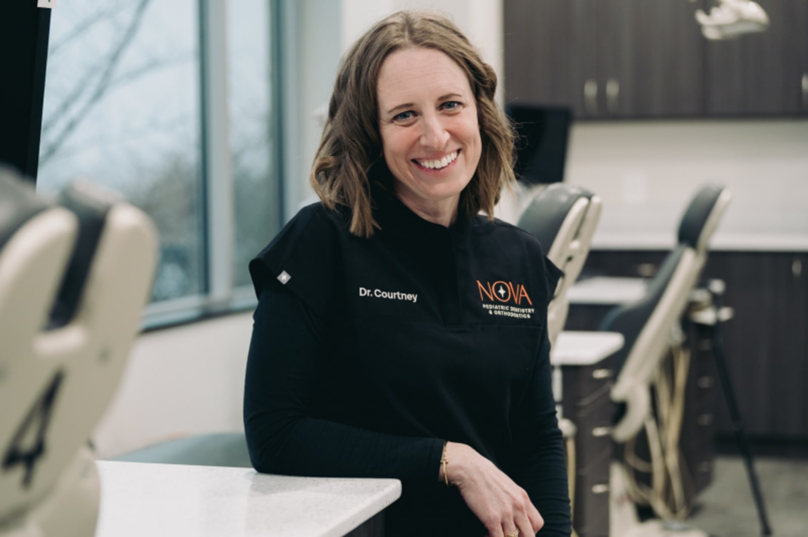 Female dentist smiling at camera in clinical setting at Nova Pediatric