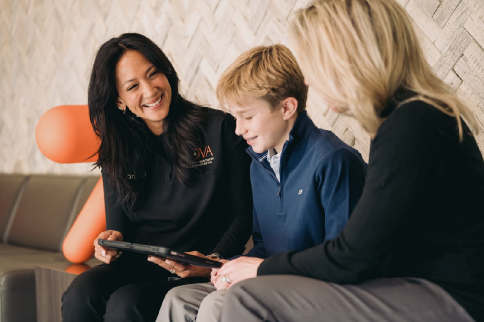 Dentist reviewing tablet with young patient and parent in office
