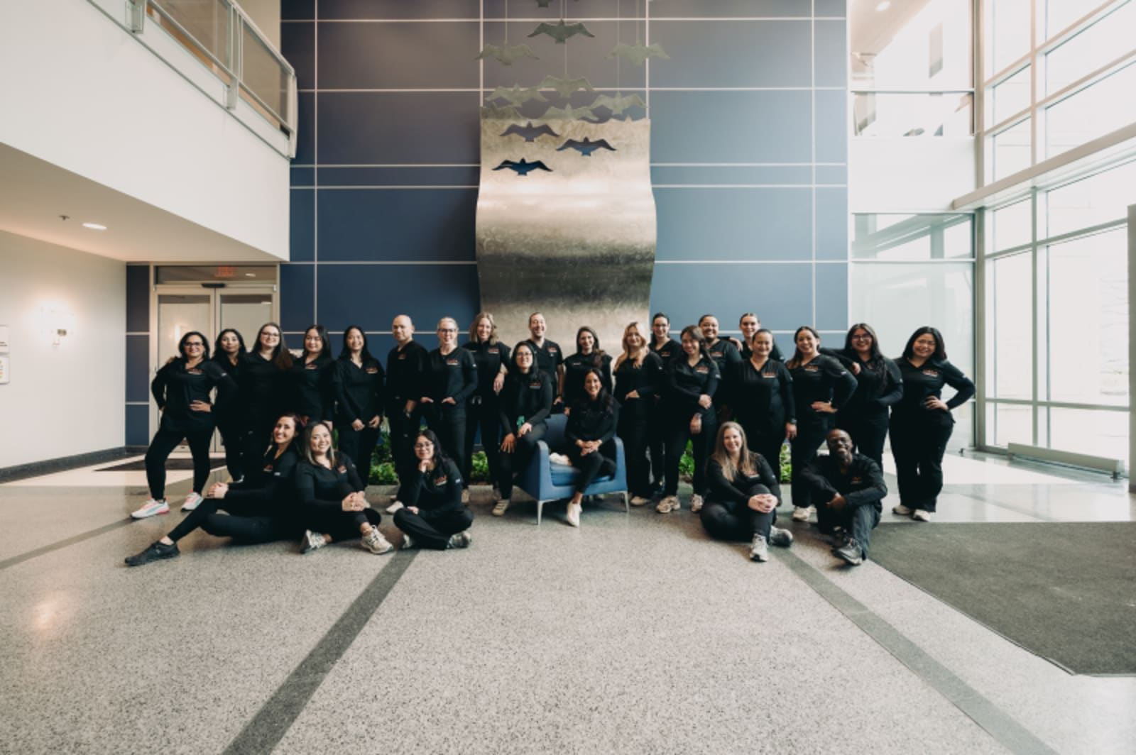 Large team photo of Nova Pediatric Dentistry staff in modern office lobby