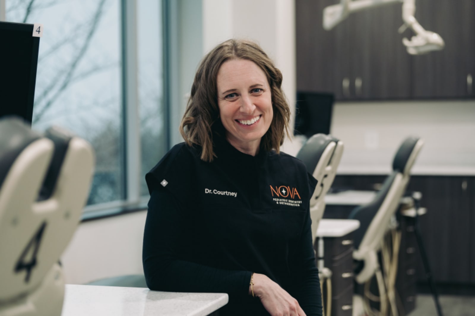 Orthodontist smiling at desk in modern dental office