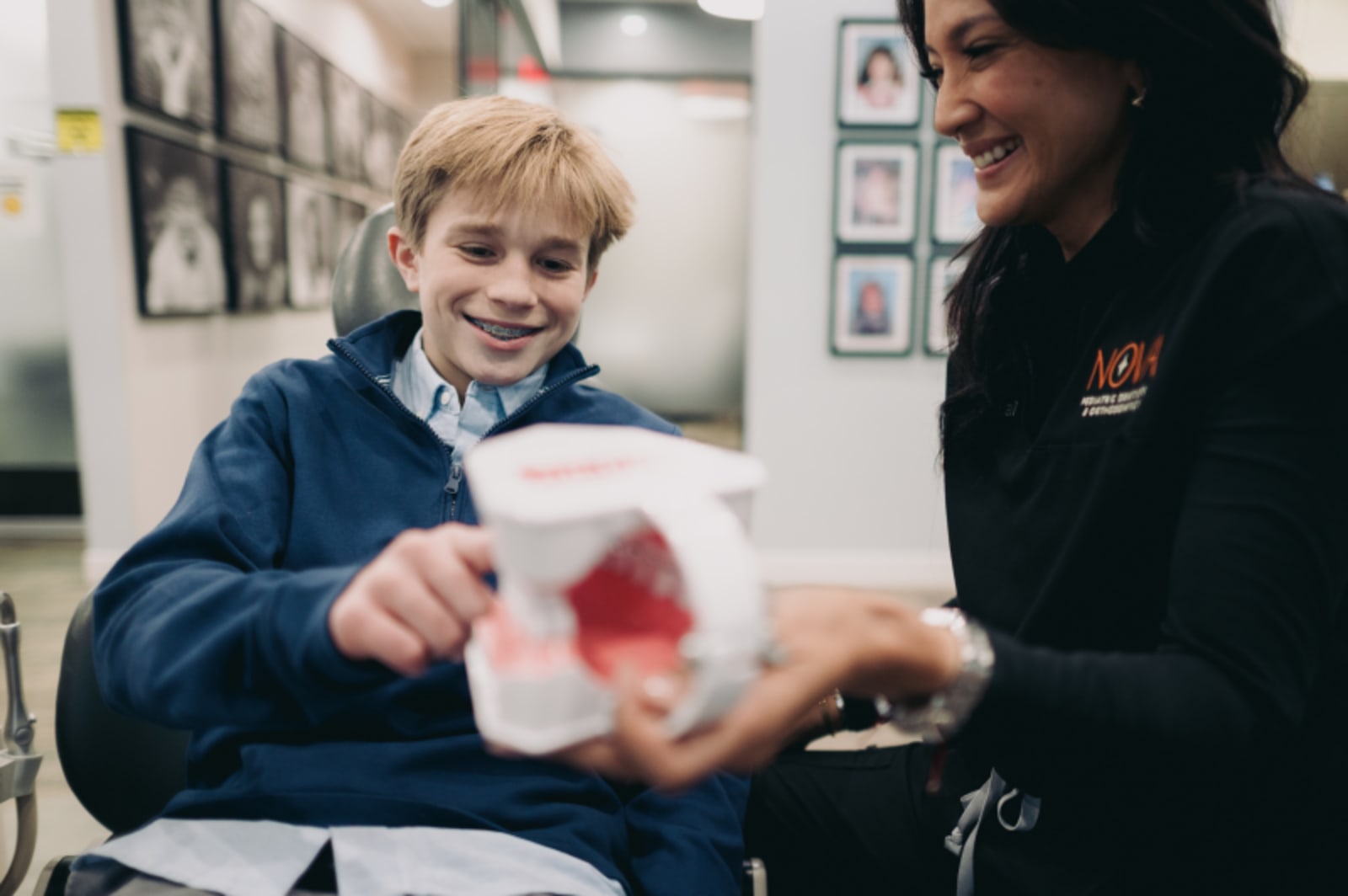 Dental professional showing clear aligner or orthodontic model to young patient