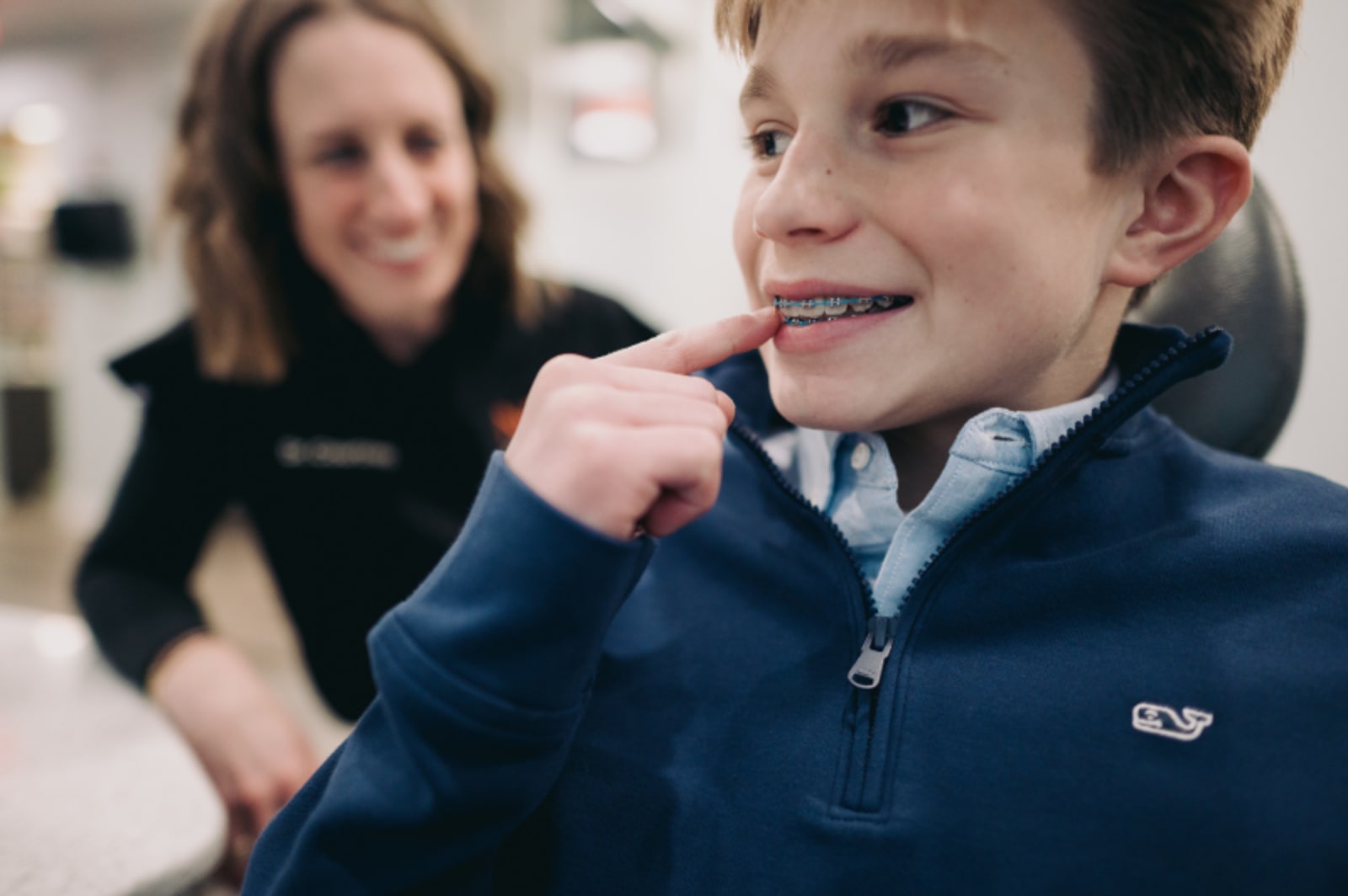 Young child smiling in dental office with staff member during exam