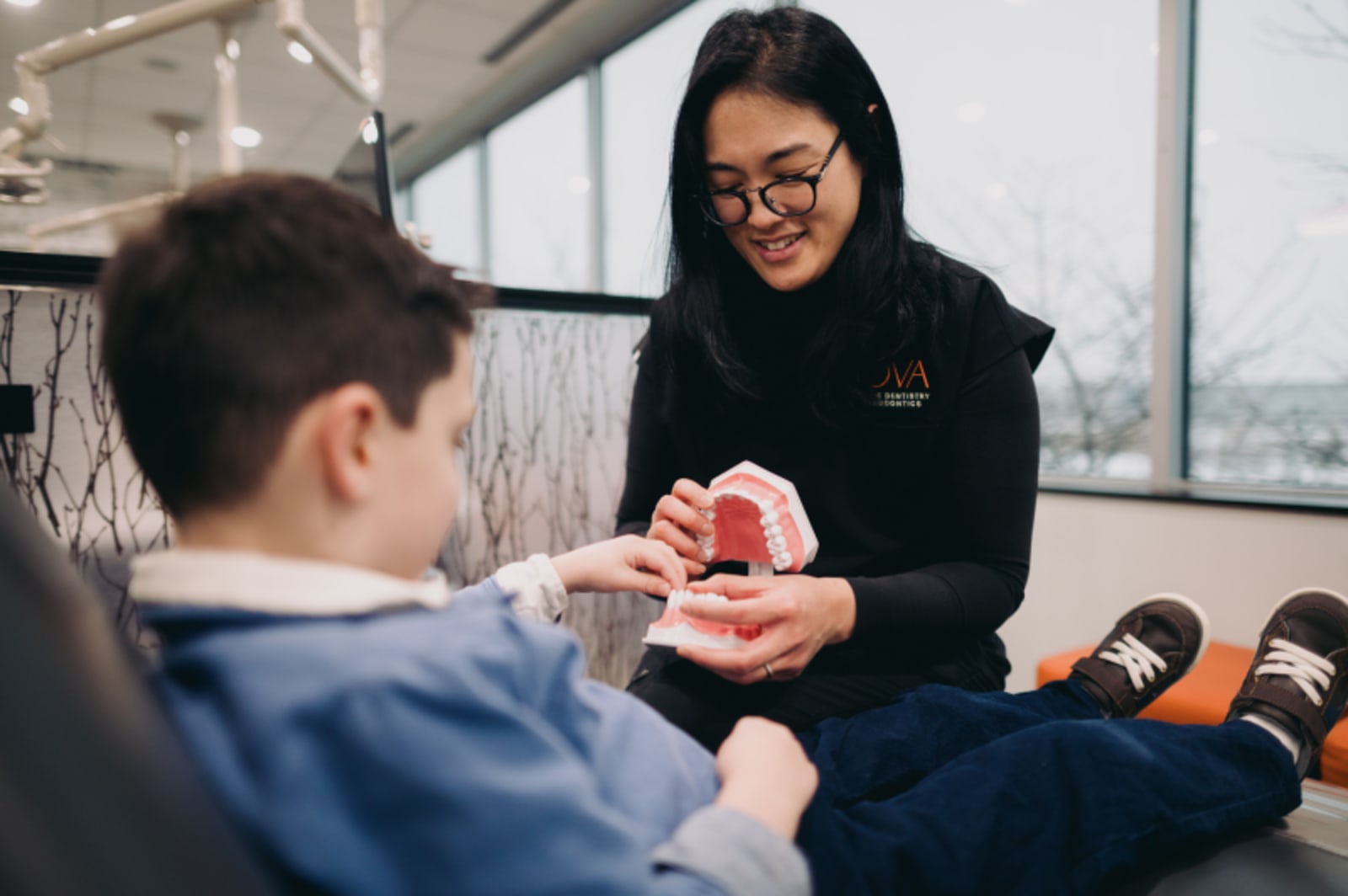 Orthodontist showing dental model to young patient during consultation