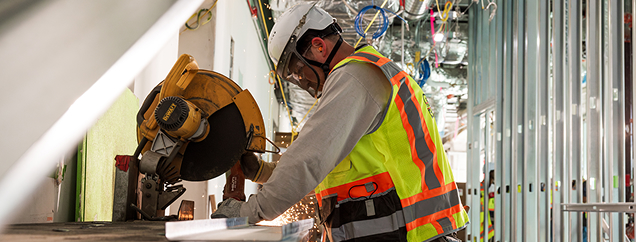 Worker cutting metal studs during interior framing