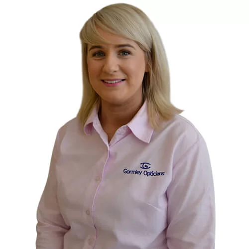 Smiling Shauna with blonde hair wearing a light pink shirt embroidered with Gormley Opticians logo.