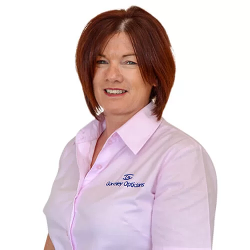 Smiling Genevieve with short red hair wearing a light pink shirt with the Gurney Opticians logo.