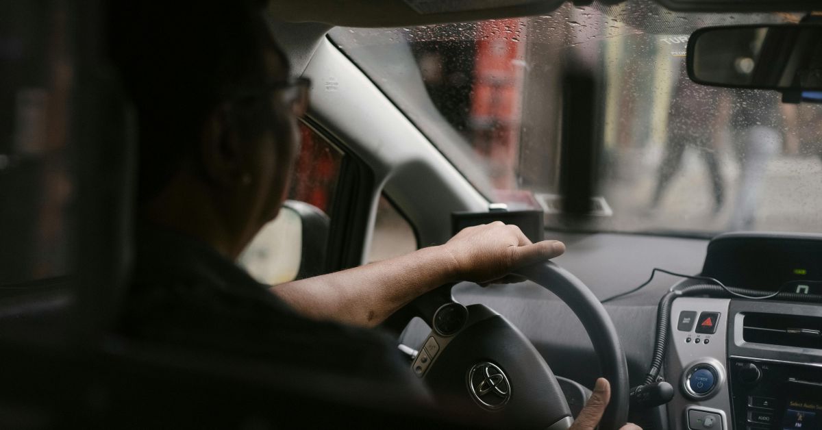 Driver behind the wheel navigating through wet rainy streets.