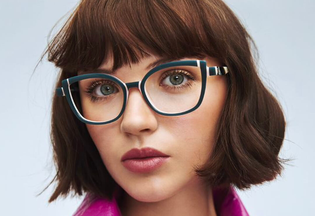Woman with bob haircut wearing dark cat-eye glasses.