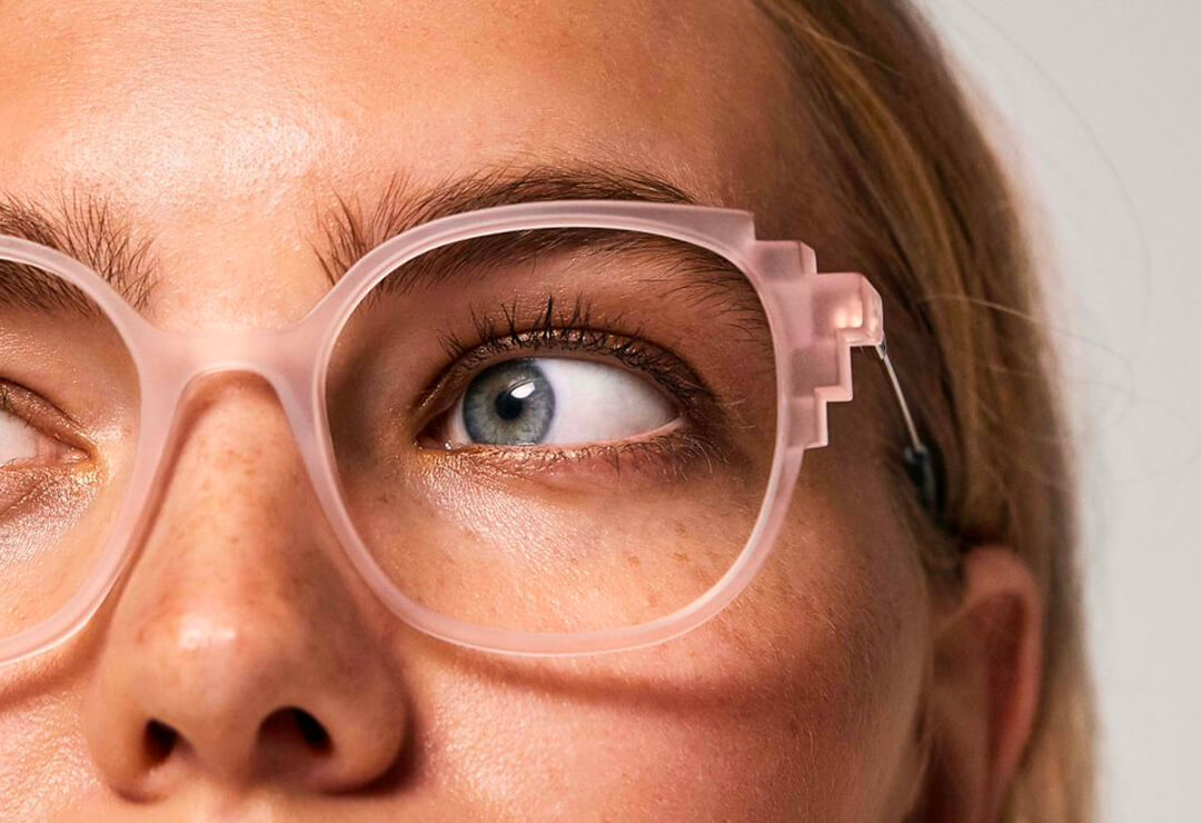 Close-up of woman wearing oversized pink transparent glasses.