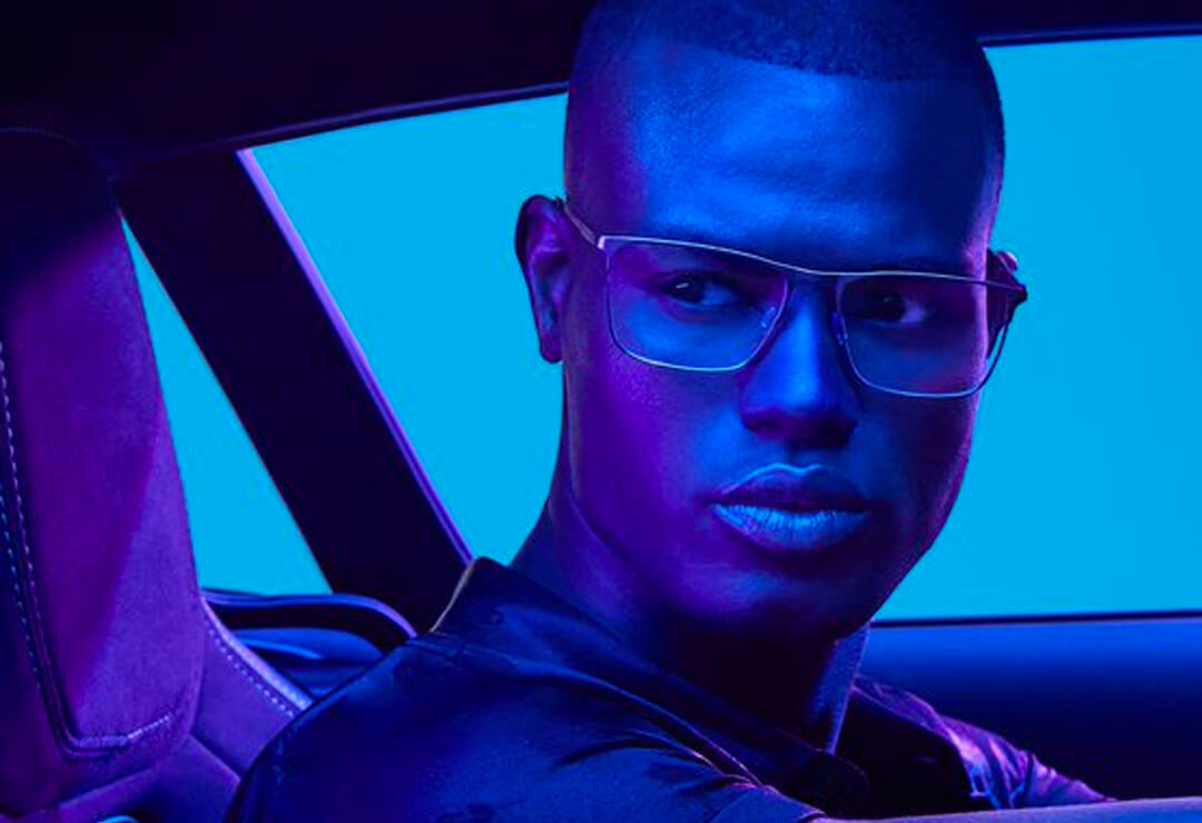 Man wearing sleek glasses frames in purple-toned lighting.