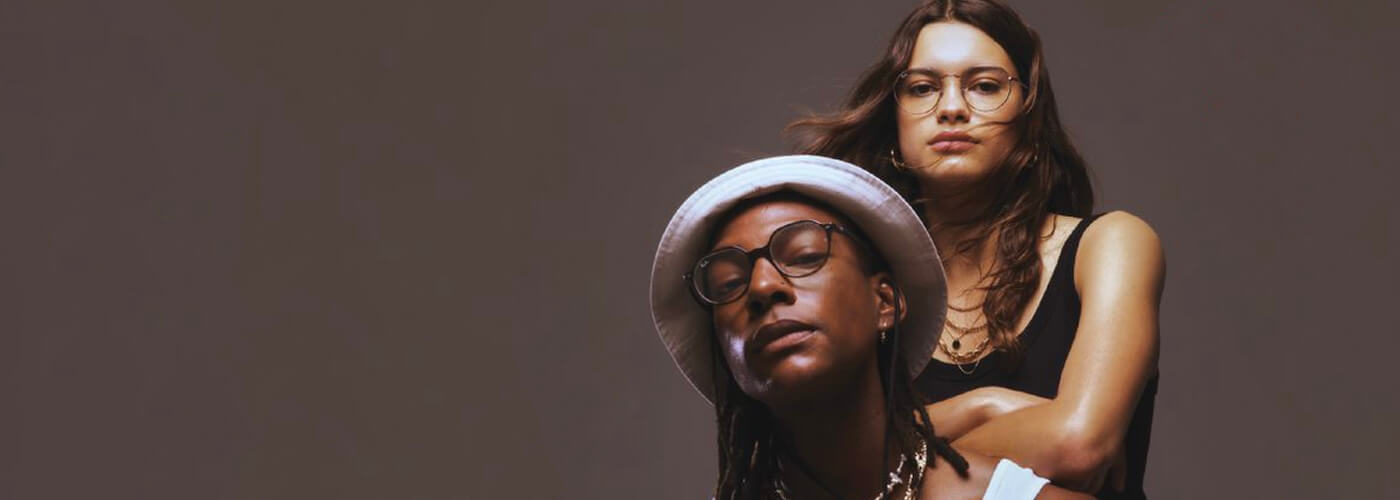 Two people wearing Ray-Ban glasses posing together in studio.