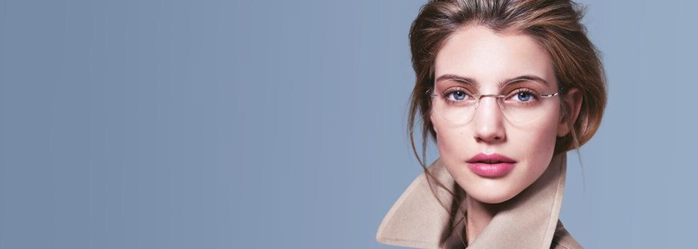 Woman wearing ultra-thin rimless Silhouette glasses against blue background.