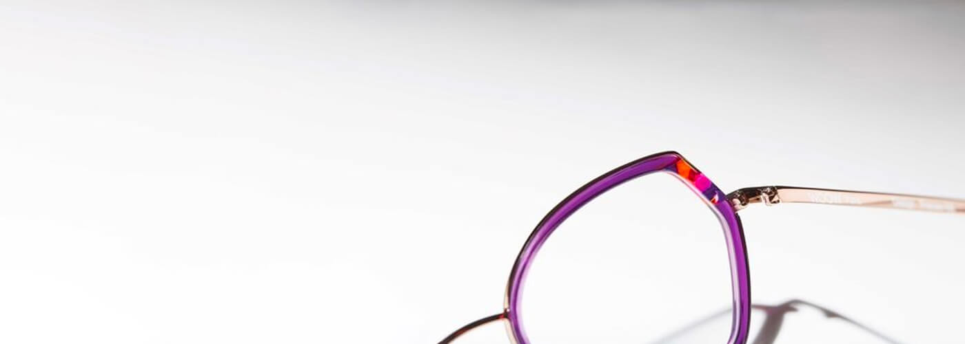 Close-up of purple geometric glasses frame with rose gold temples.
