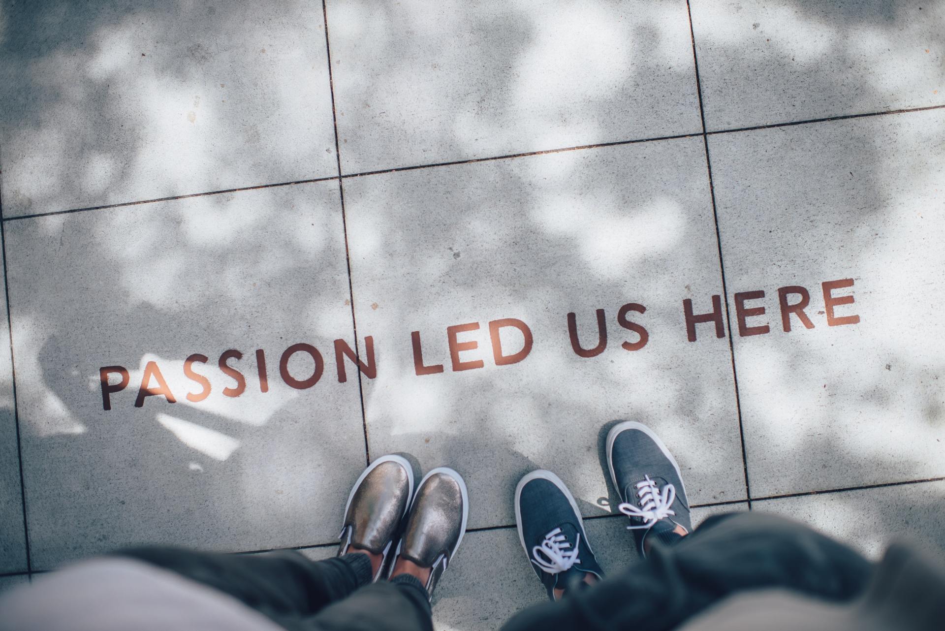 Feet standing on pavement with the inscription "PASSION LED US HERE," symbolizing dedication and motivation in the context of creating engaging blog content.