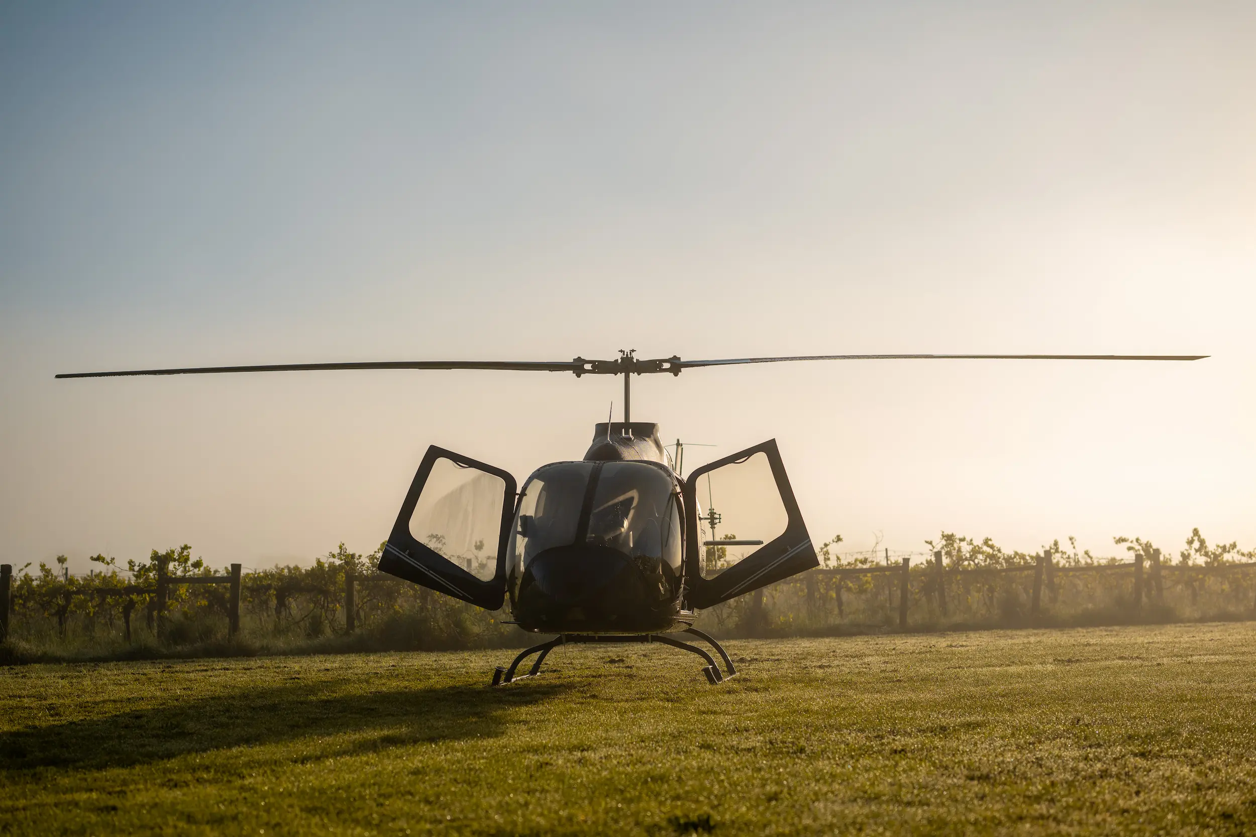 A helicopter sitting on top of a lush green field.