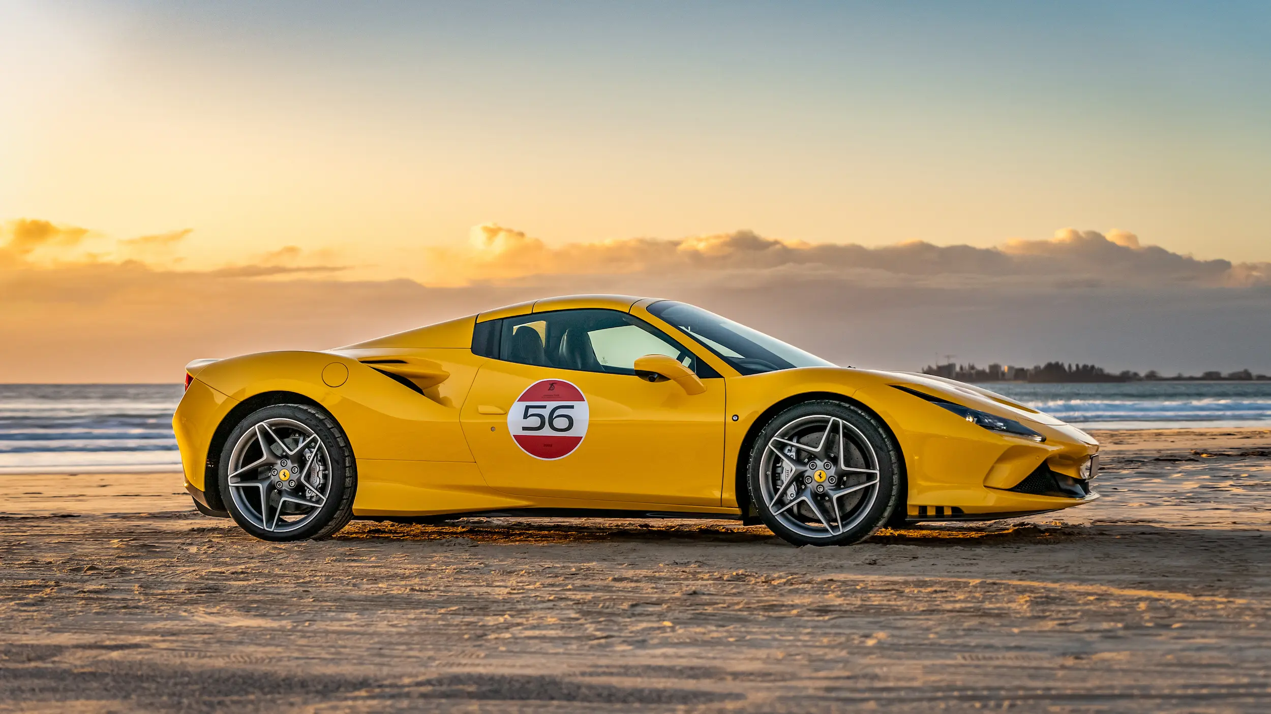 A yellow sports car parked on the beach.