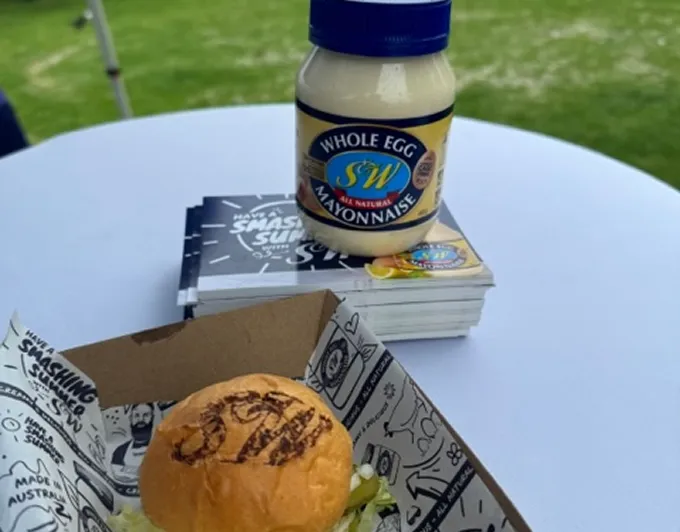 A sandwich and a jar of mayonnaise on a table.