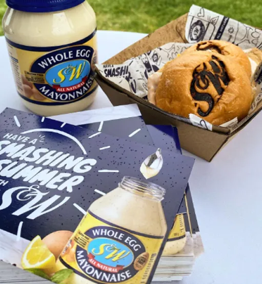 A table topped with a box of food and a bottle of mayonnaise.
