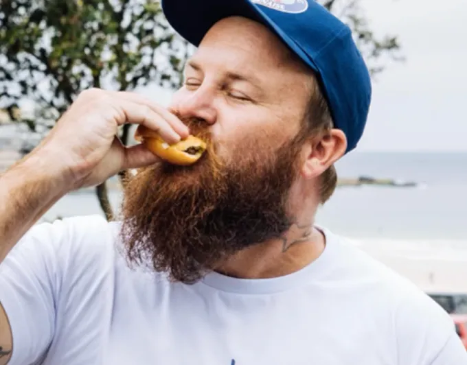 A man with a beard eating a donut.