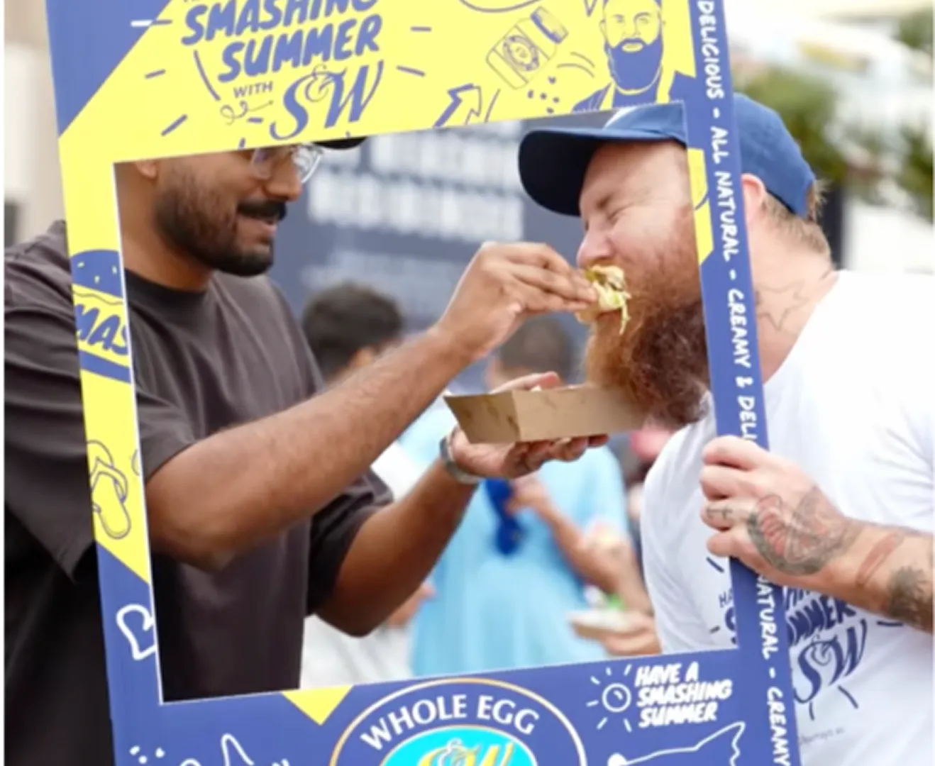 A man eating a slice of food while standing next to another man.