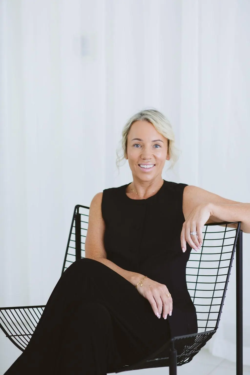A woman in a black dress sitting in a chair.