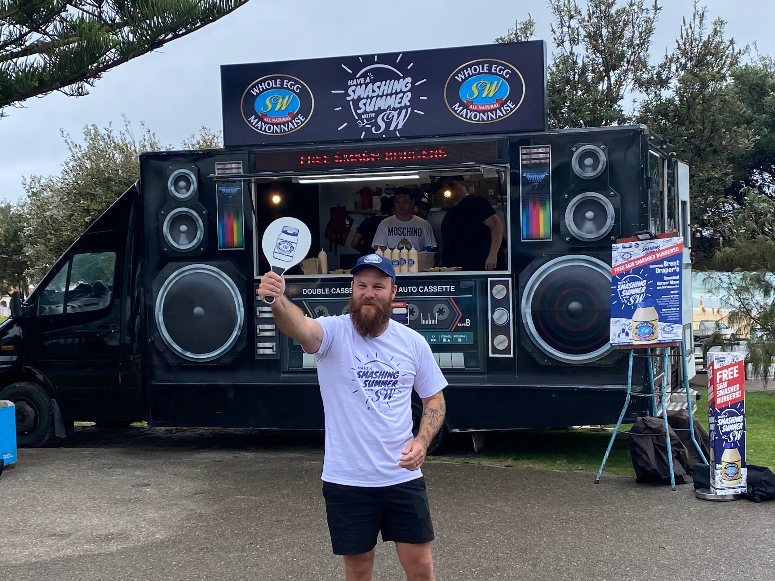 A man holding a frisbee in front of a food truck.