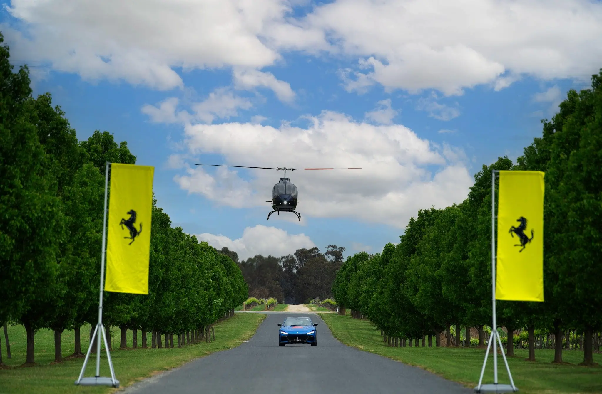 A helicopter flying over a car on a road.