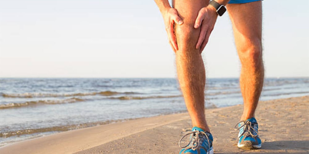 Close-up of a person stretching a leg muscle in a clinic, representing muscle twitching causes for PhysioLocal.